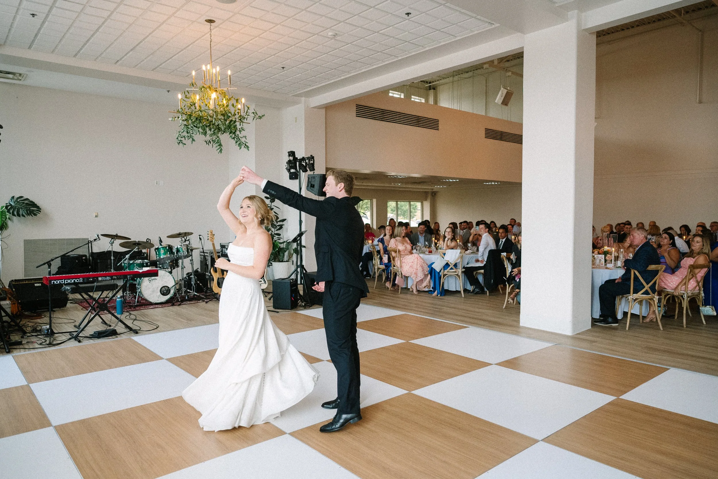 Arbor at the Port bride and groom dancing at their wedding reception in a bright modern ballroom with guests and live band in Rochester, NY.