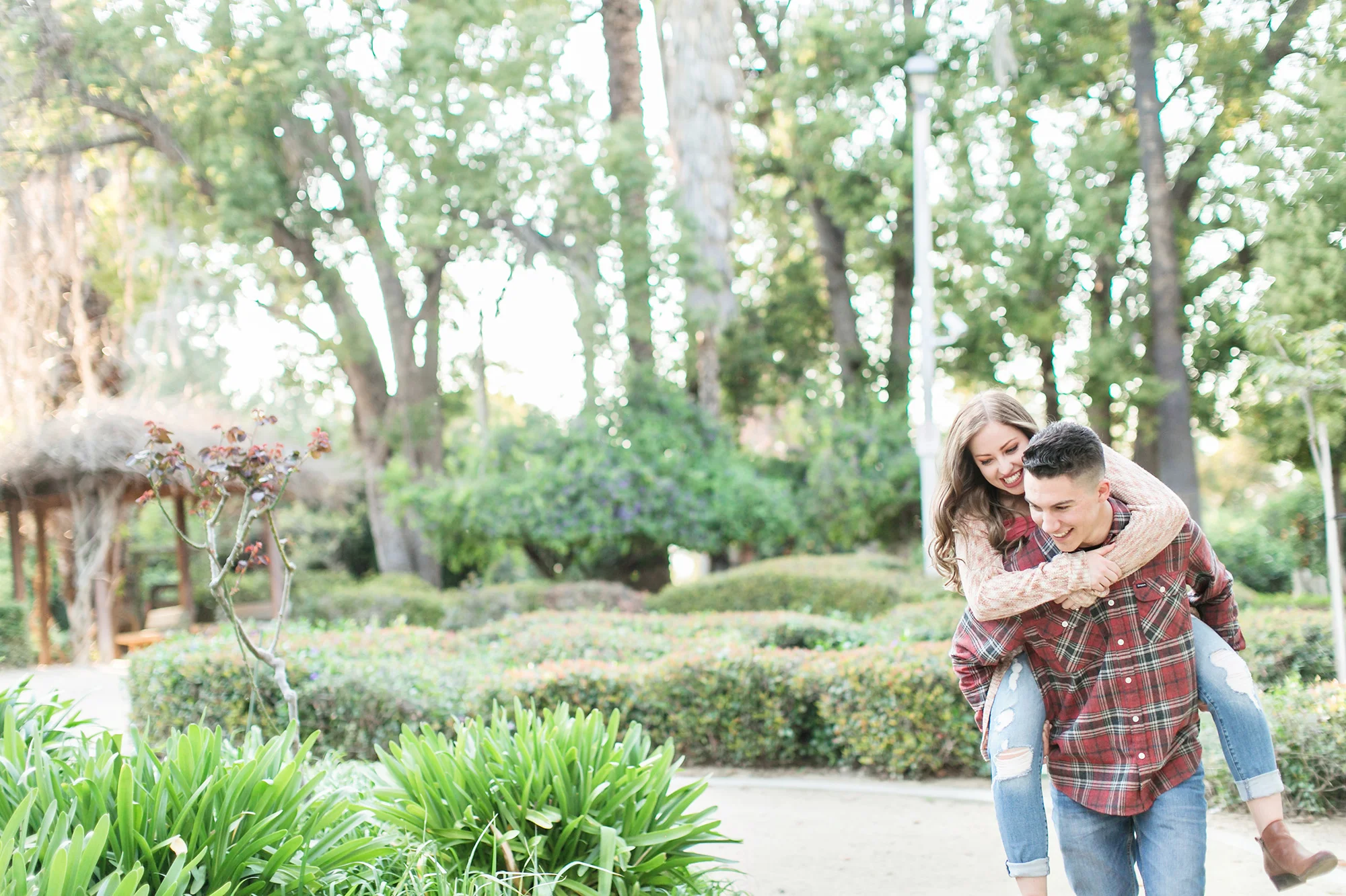 Engaged couple giving piggy back ride during engagement session at Sylvan Park in Redlands, Carrie Vines Photography