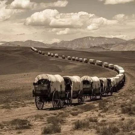 A wagon train crosses a wide Western landscape beneath a cloudy sky, part of the visual research for Cowboys and Cancer.