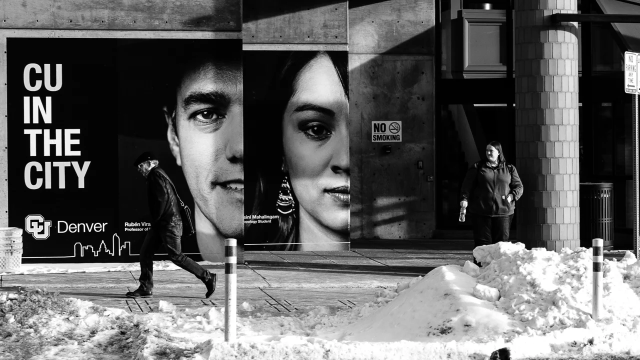 Day 67- 365 Day B&W Photo Challenge - Walking in front of the "CU in Denver" advertisement in front of the University of Colorado Denver Campus building. - Fuji XT35 XF 35mm f/2, Acros R Film Simulation