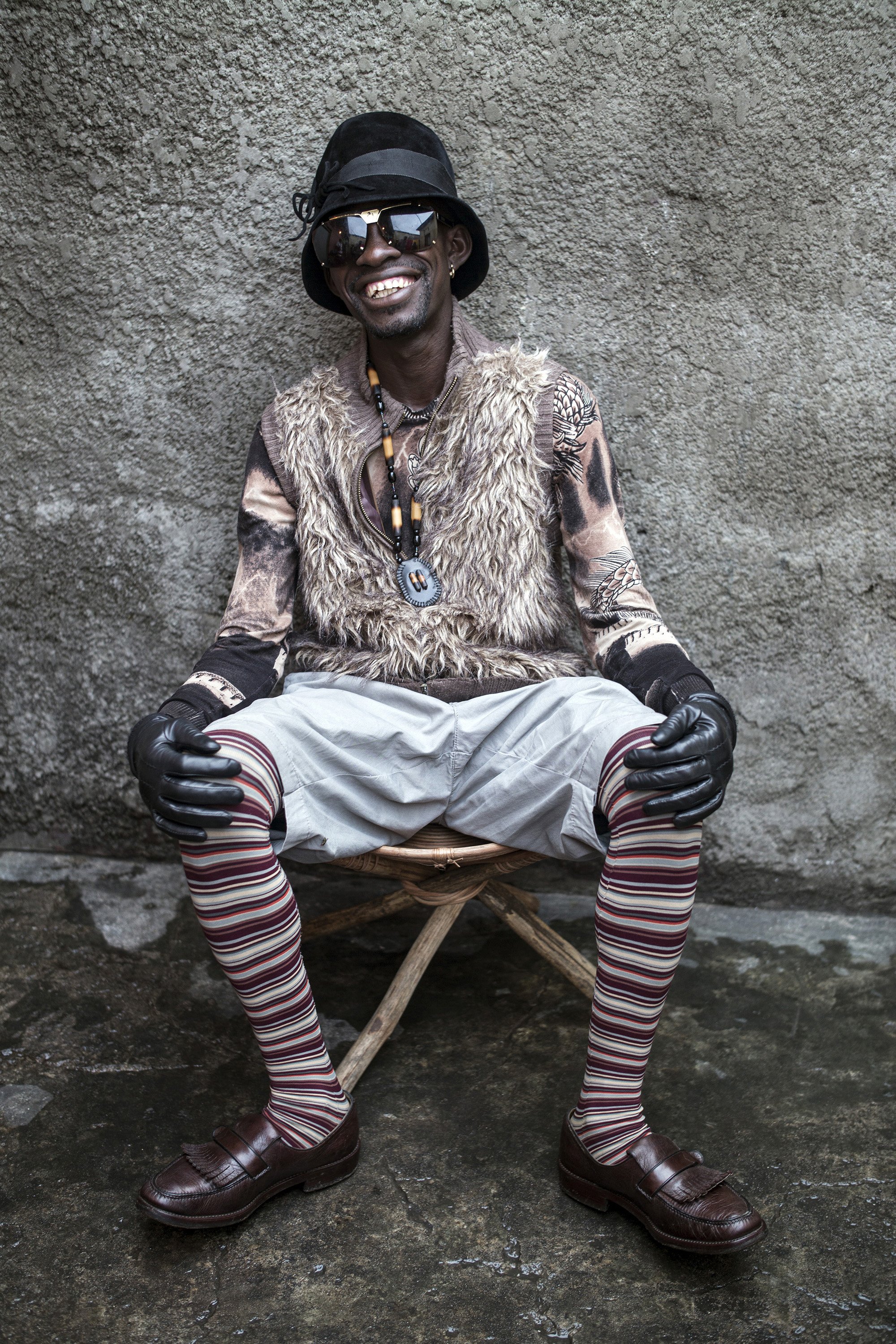  A Sapeur member of Leopards group sits in a backyard in Kinshasa, DRC. SAPE is to dress with “elegance and style". Many Sapeurs are unemployed, poor, and live in harsh conditions in Kinshasa, a city of about 10 million people. For many of them being