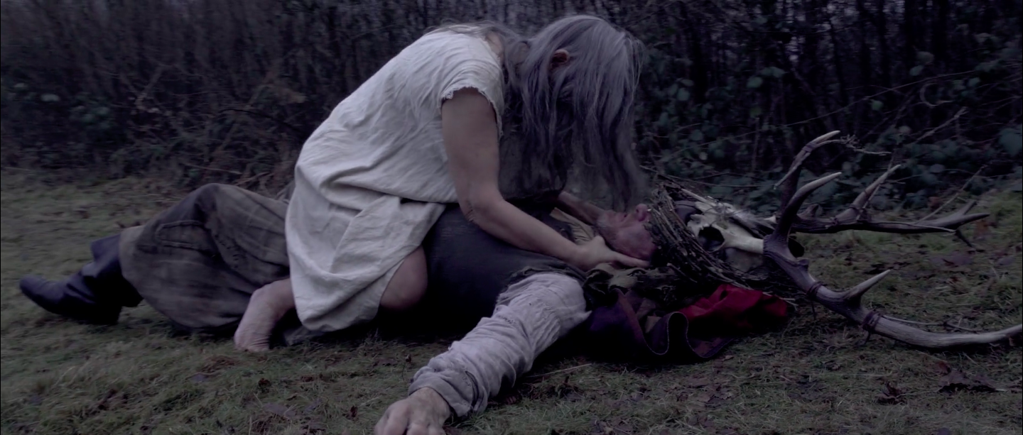 EXT. WOODLAND - The witch performing the sacrifice with the antler crown