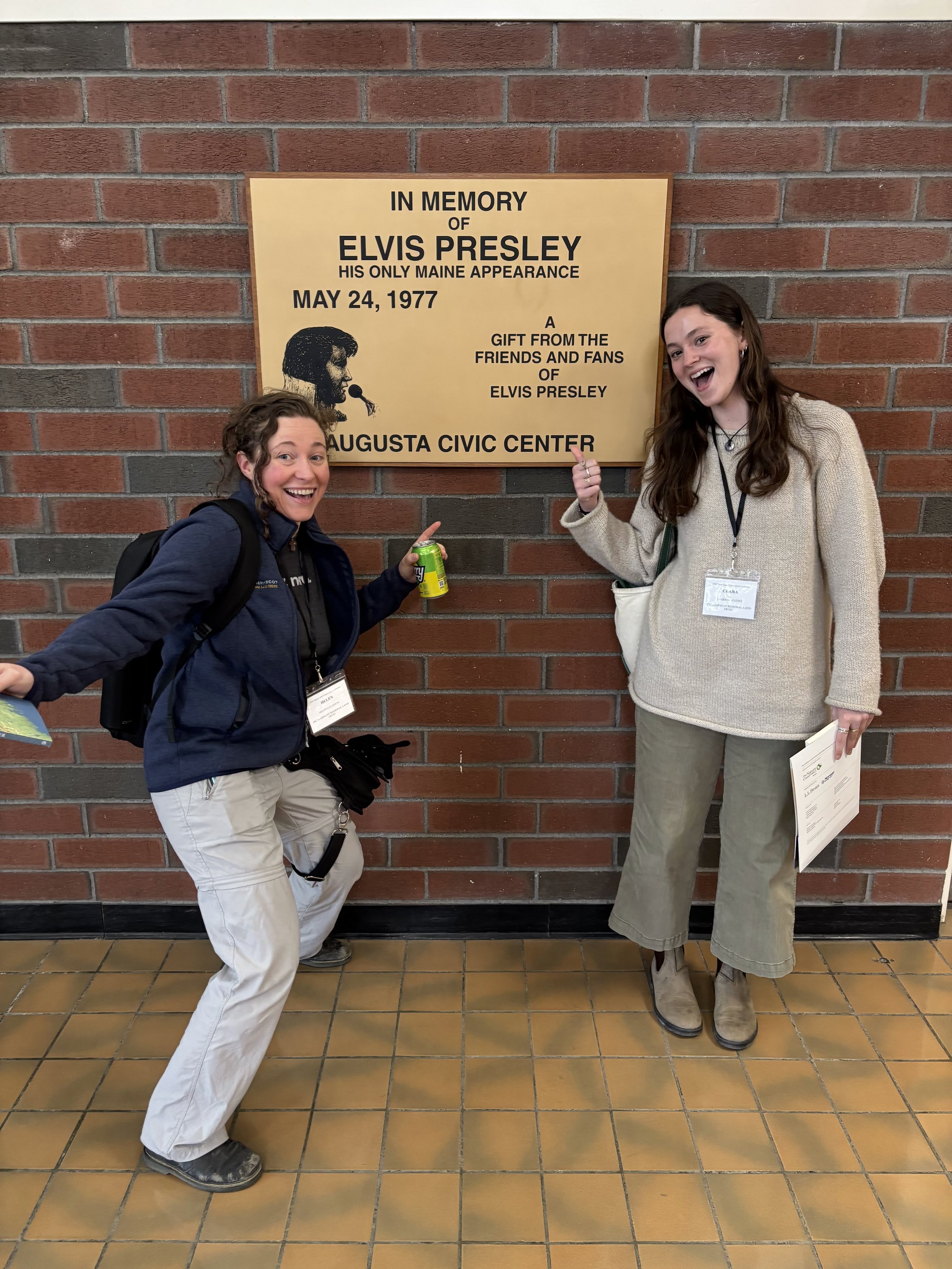two staff members doing silly poses by the Elvis plaque