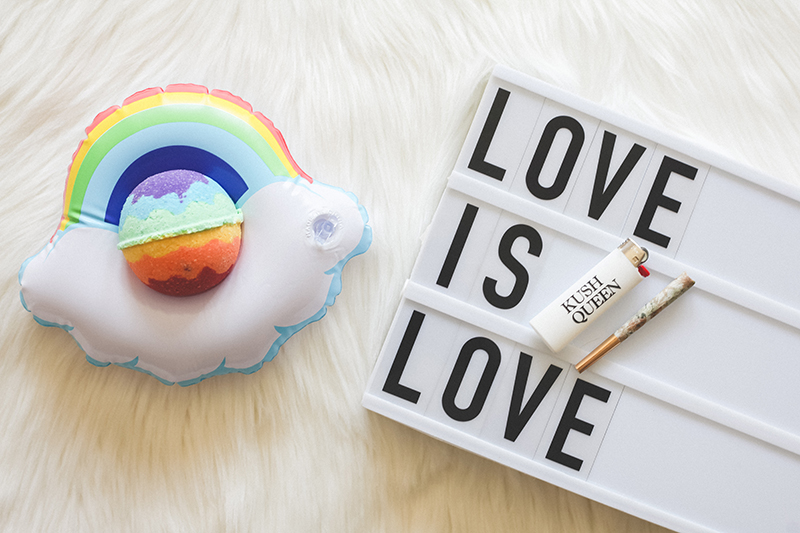 Rainbow Pride CBD Bath Bomb by Kush Queen featured on mini Rainbow floaty next to sign reading Love is Love.