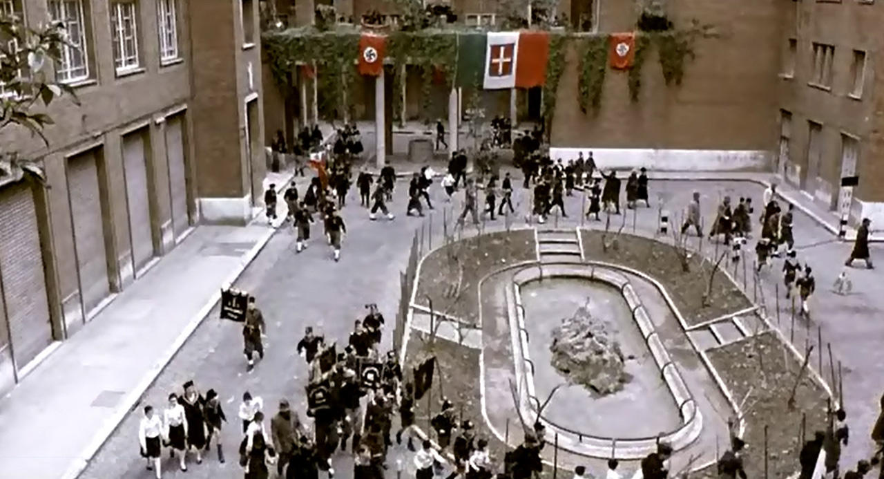 In the courtyard of a Roman apartment block, residents head to a military parade in Hitler’s honor