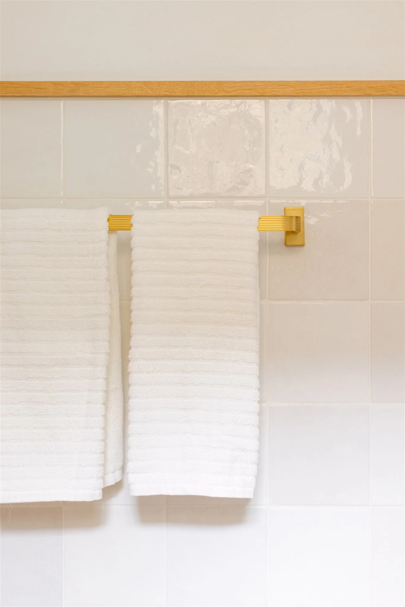 white tiles with brass towel bar and wooden chair rail.