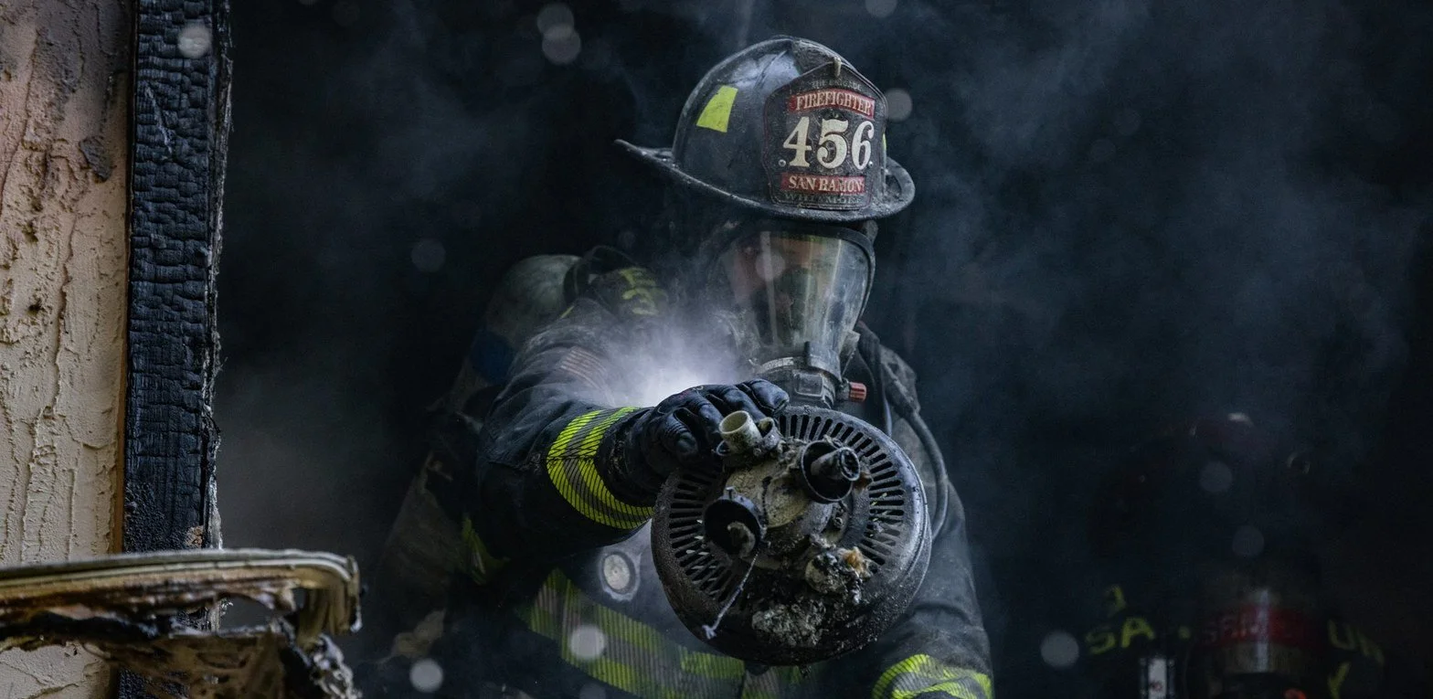 San Ramon Valley firefighter operating a hoseline in a burned structure