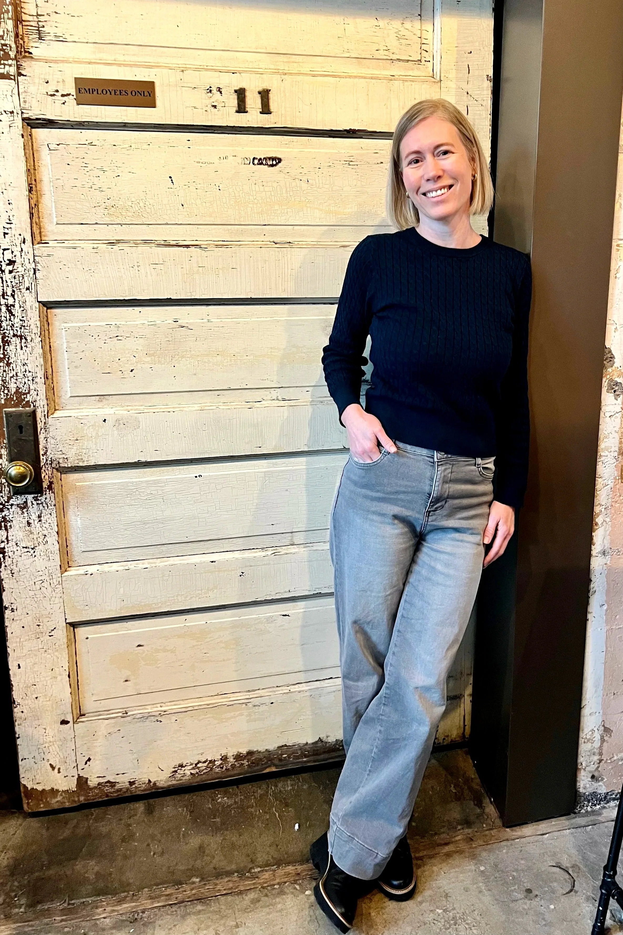 Lis Thomas standing with a navy top by a door