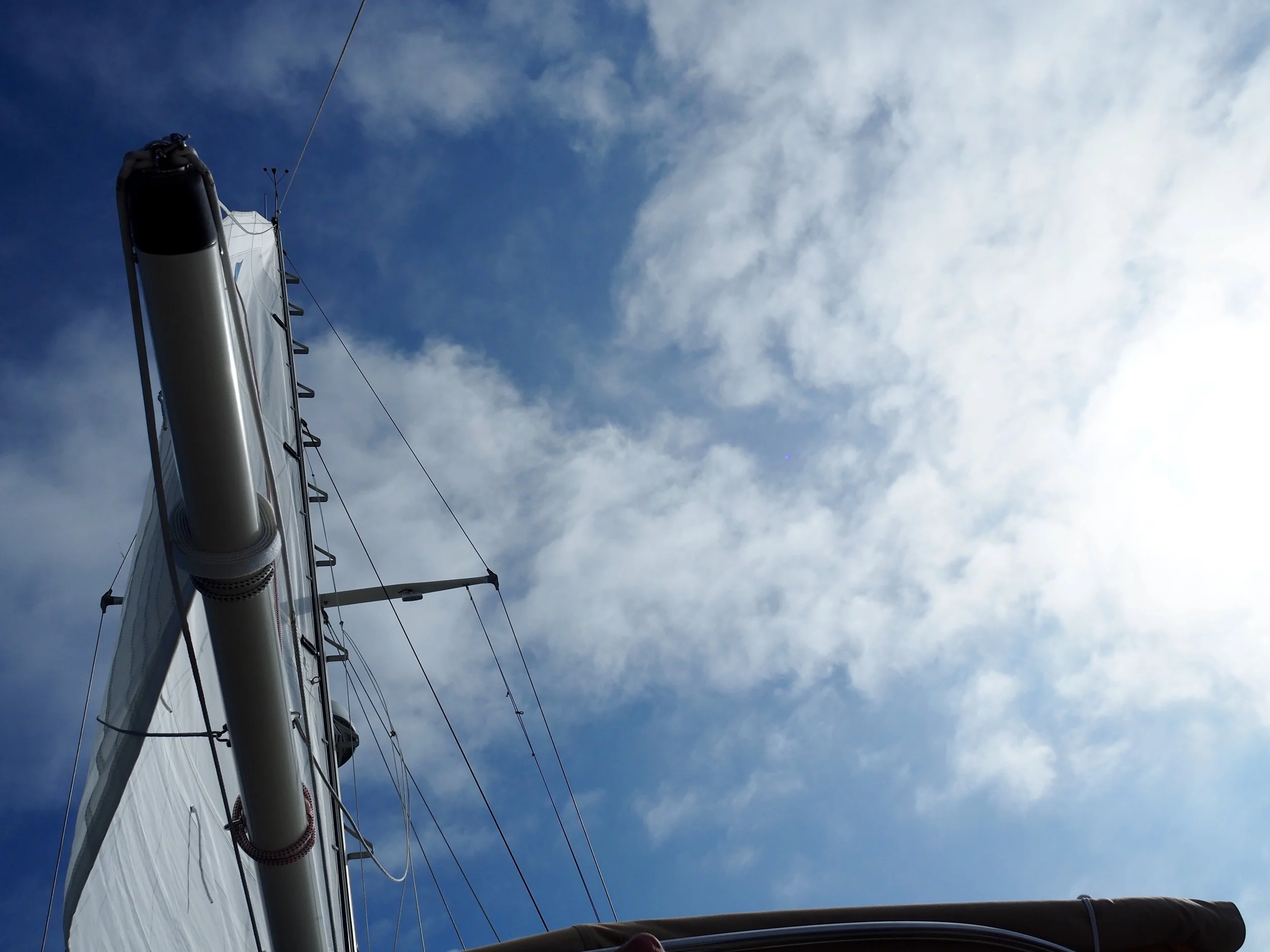 The peace of a full sail and a blue sky. Also of a boat so well balanced — even close hauled — you can lie back in the cockpit and see the world this way.