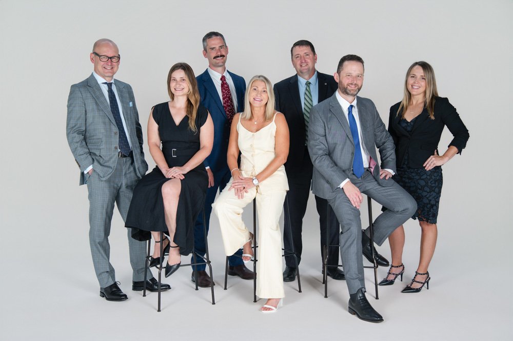 3 women and 4 men wearing business attire in a group and smiling