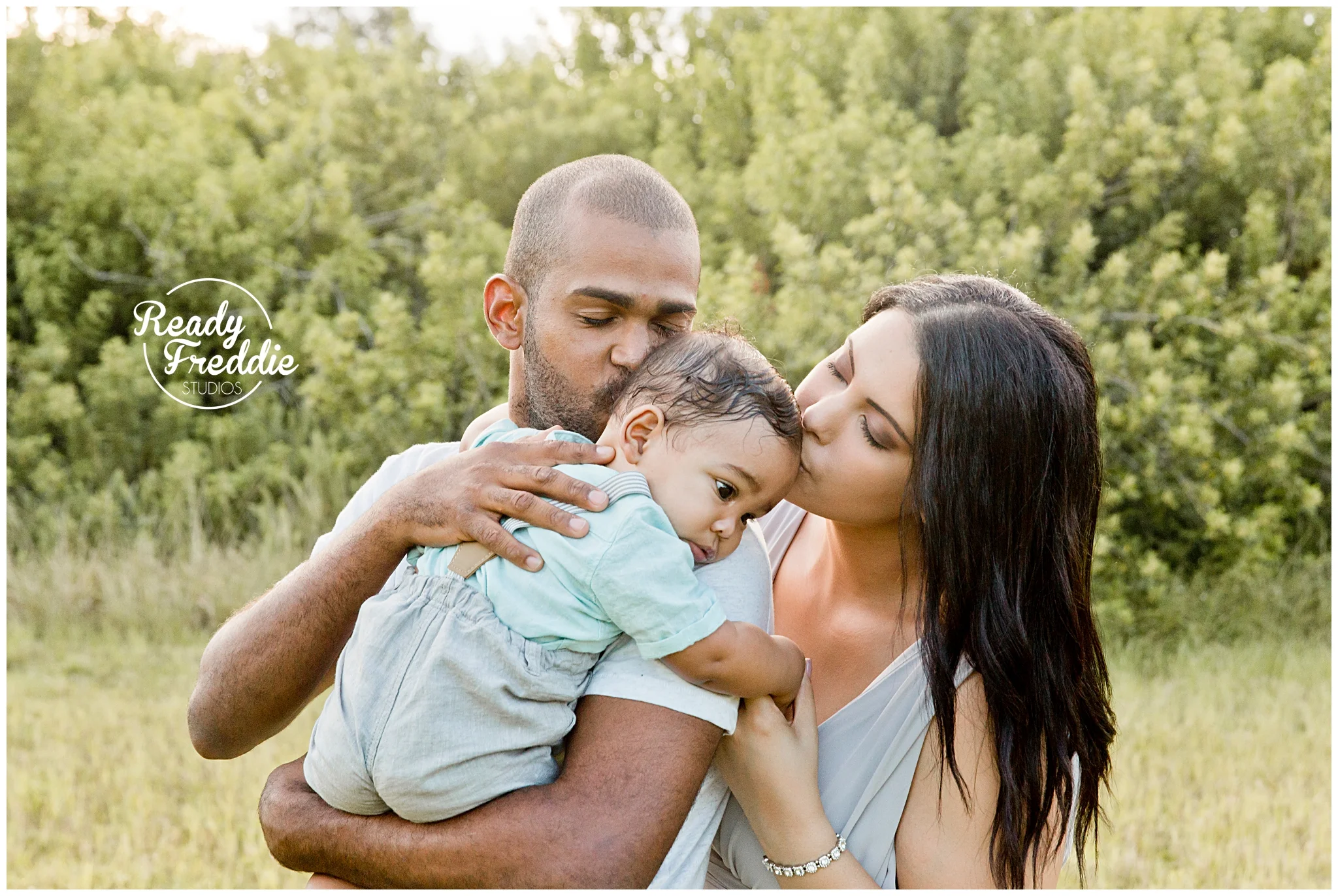 mom and dad both kissing baby