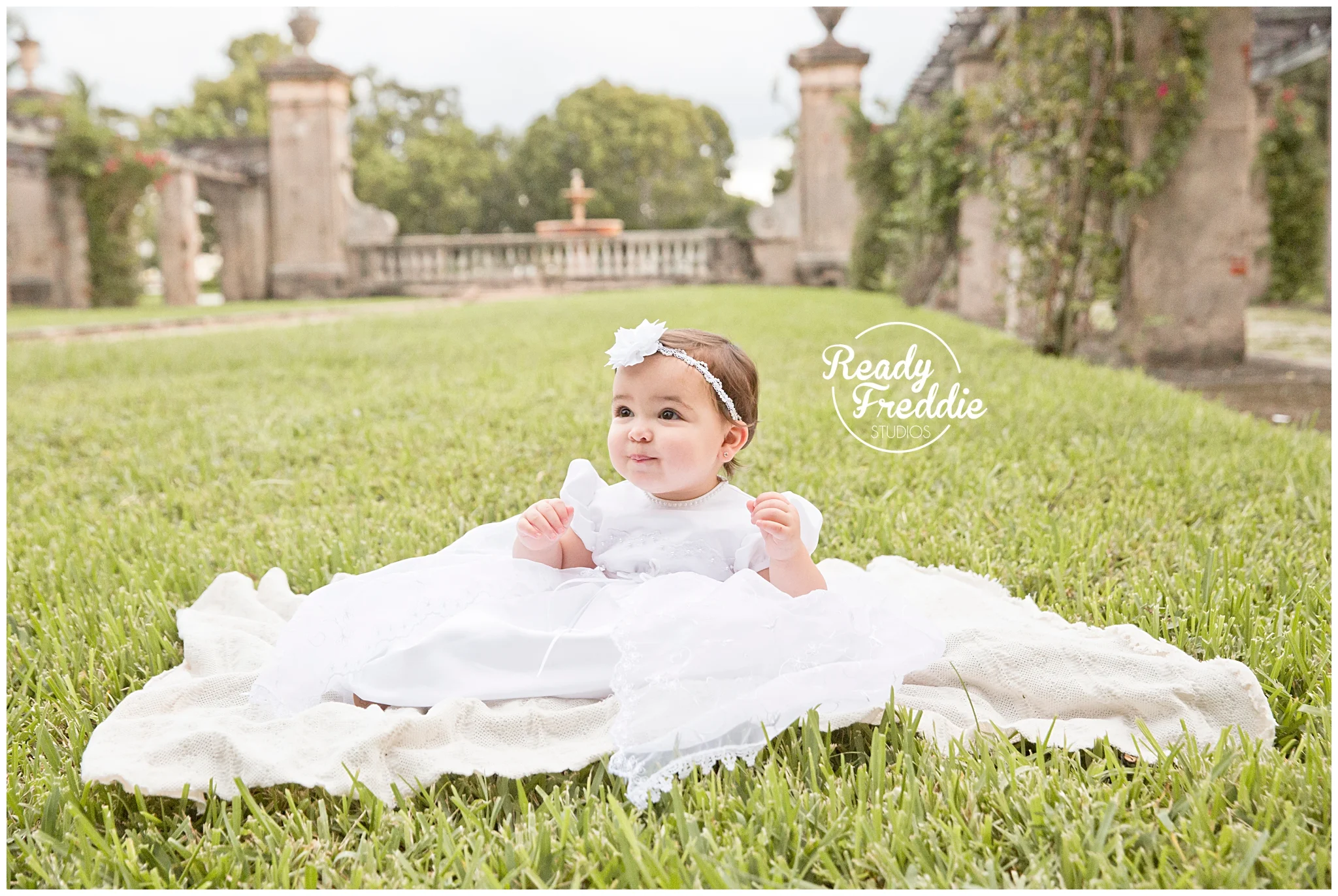 One year old sitting down in her baptism gown