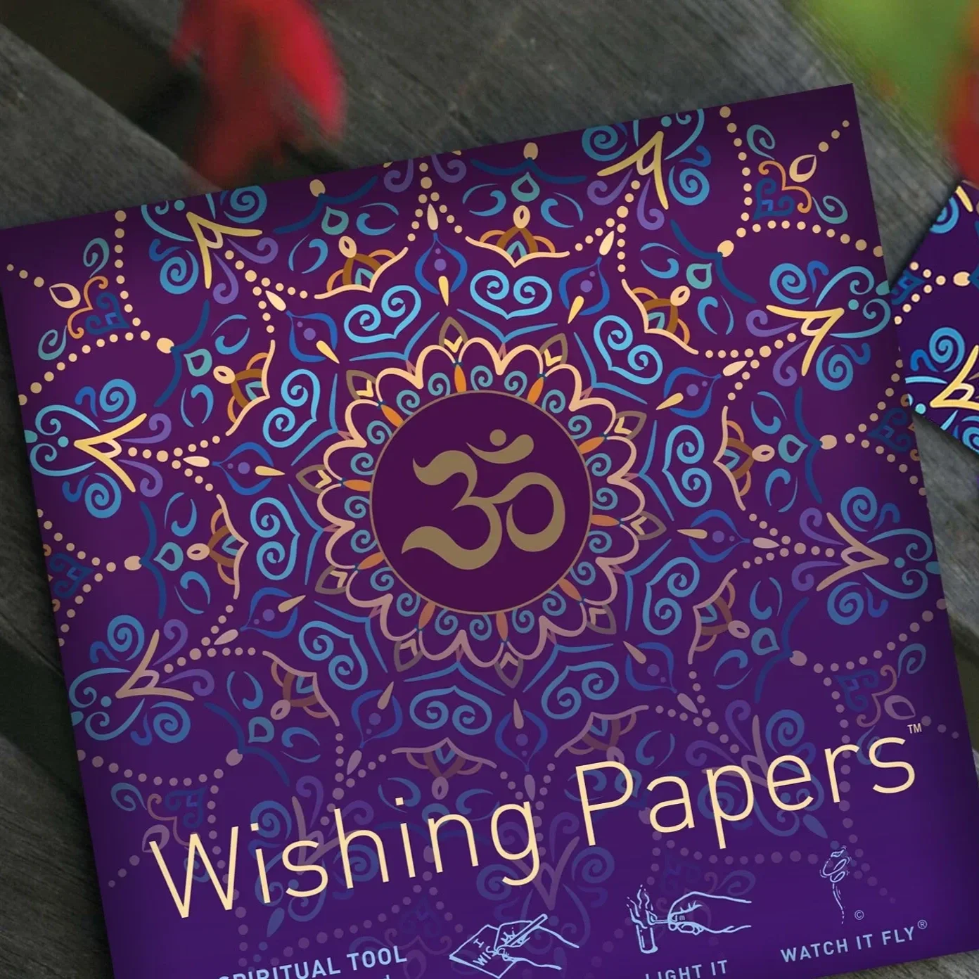 Purple box of Wishing Papers with intricate gold, blue, and purple mandala design and the Om symbol in the center.