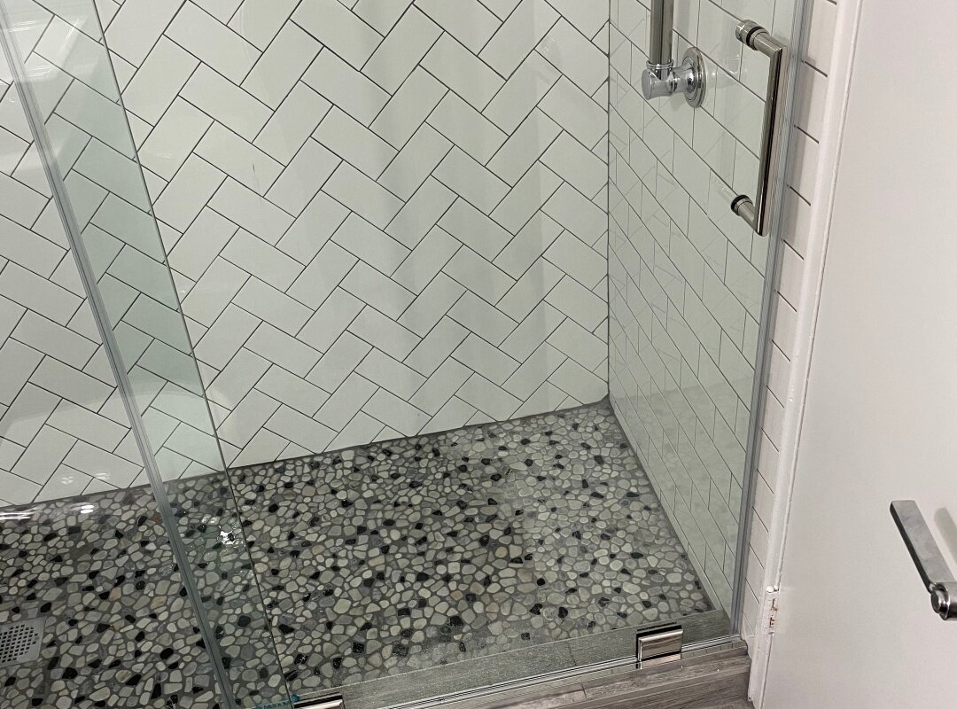 Bathroom white subway tiles in herringbone pattern with pebble shower floor_queens apartment.jpg