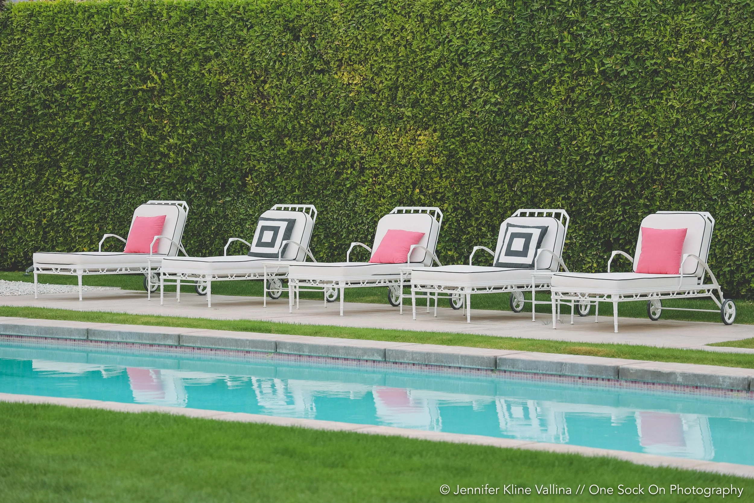 pool with lounge chairs and pink pillows and geometric pillows
