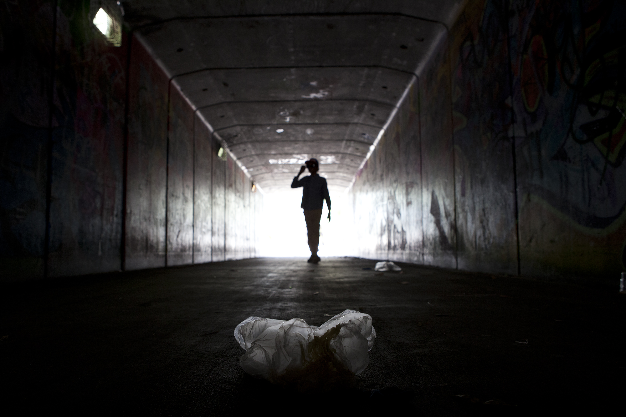  A dark tunnel on the outskirts of Rockhampton, littered with scrunched up plastic bags which have been filled with glue or paint used for sniffing. 