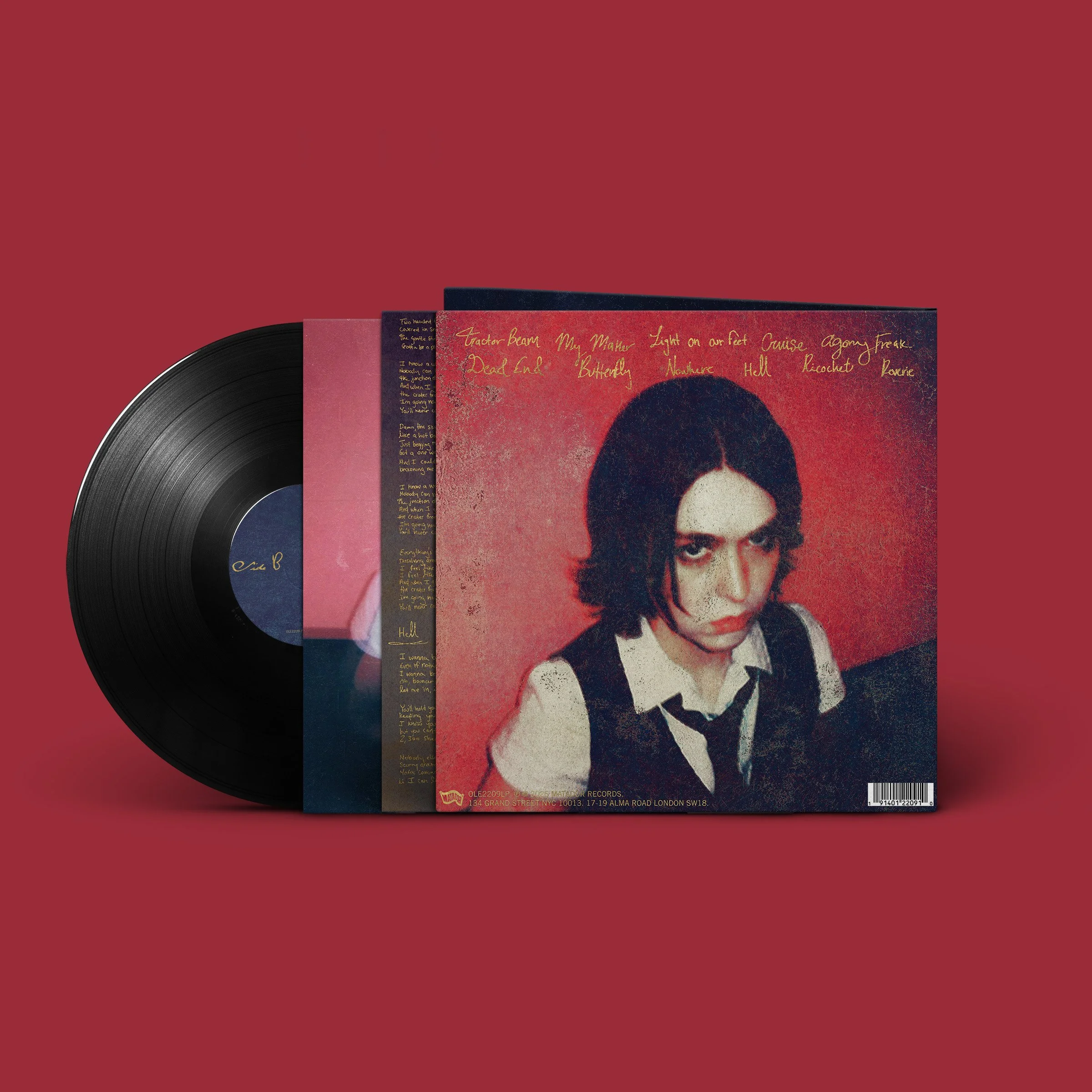 A vinyl record and album cover with a woman's portrait, dark hair, wearing a white shirt with a black vest and tie, set against a red background.