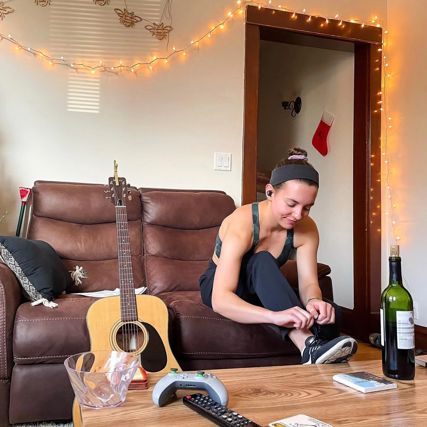 My winter break in a single picture. 
&bull;
📸: @sjfunkyfresh 
&bull;
&bull;
&bull;
ID: Jamie is sitting on a brown couch, tying her right black Nike shoe. They&rsquo;re also wearing black pants and a green workout tank. To her right is her acoustic