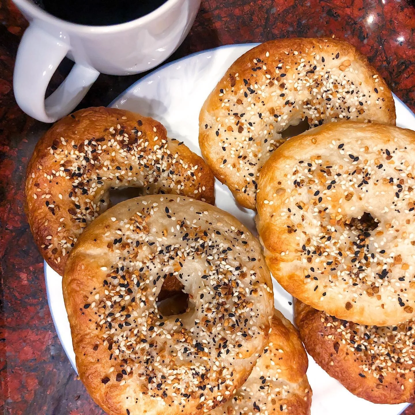 I suppose there are worse coping mechanisms than stress-baking ⍨
&bull;
&bull;
&bull;
ID: six homemade everything bagels on a white plate. A white mug of coffee on the upper left corner. The counter is red and black granite.