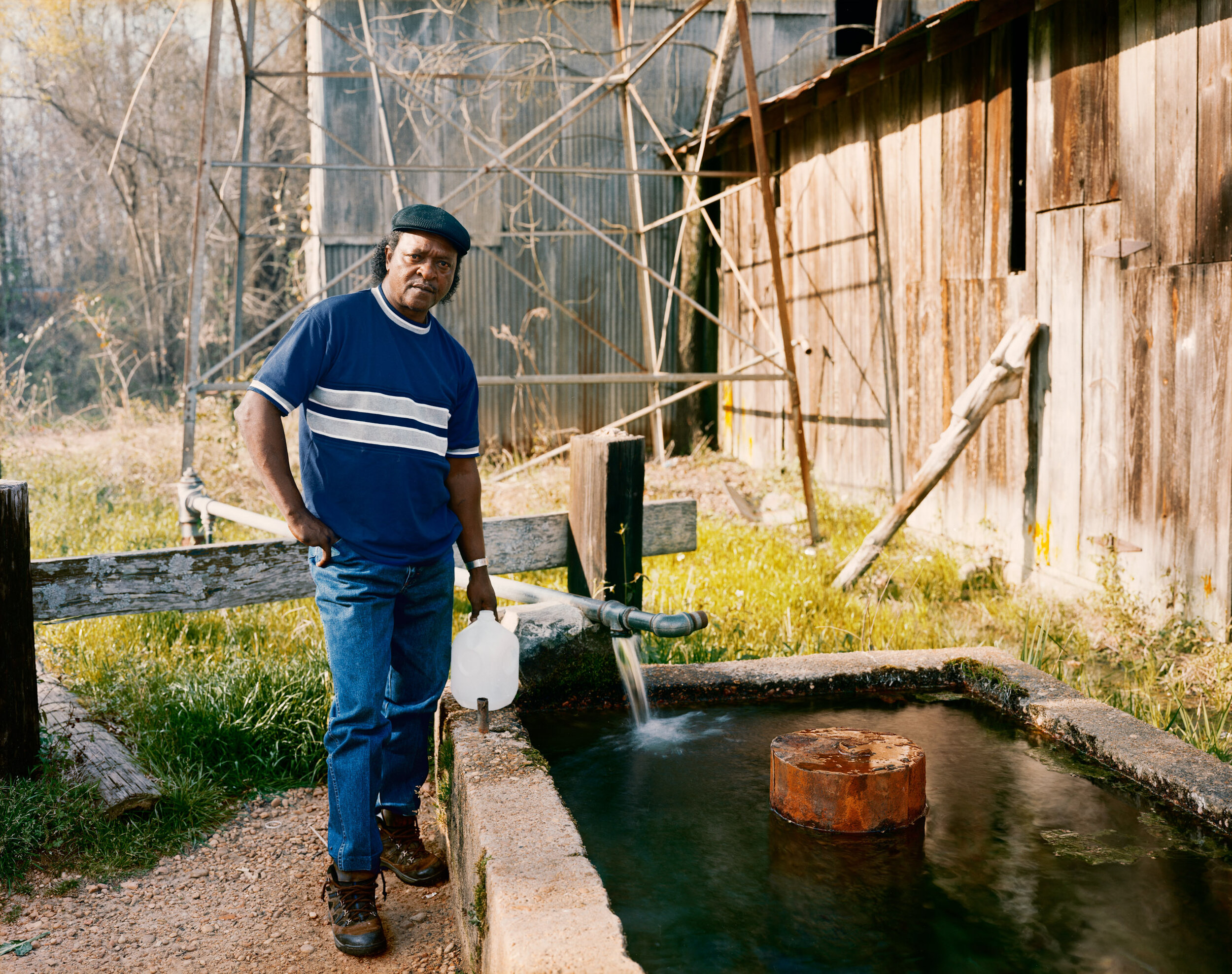 A Man Filling Bottles at a Spring behind the Cotton Gin in Sprott, Alabama, April 1999