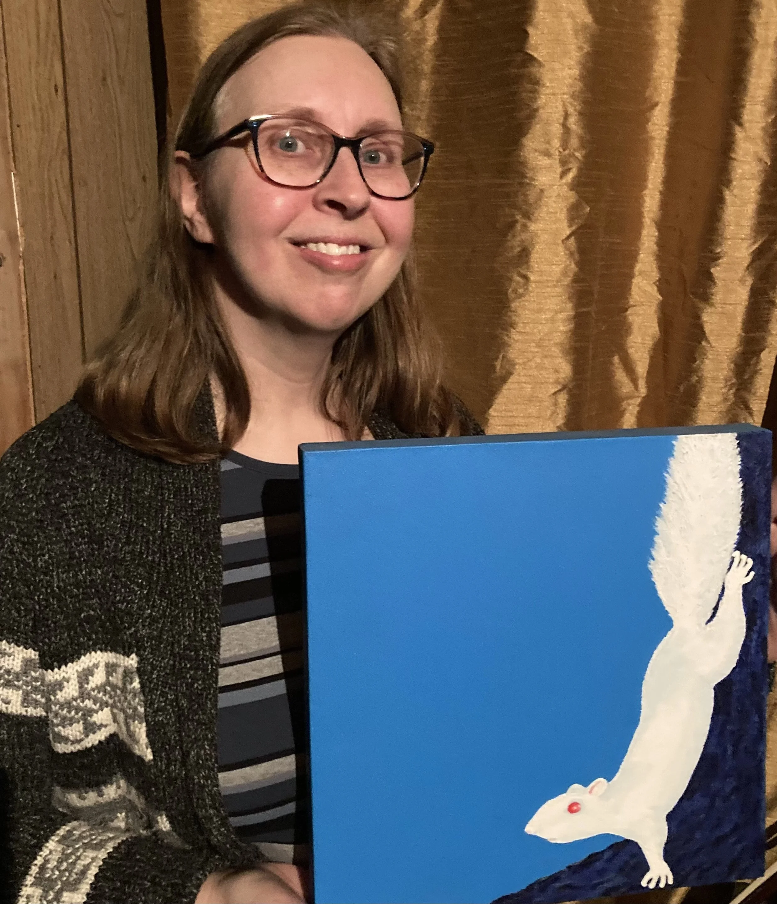 Susan Robinson holding her painting of a squirrel on a tree