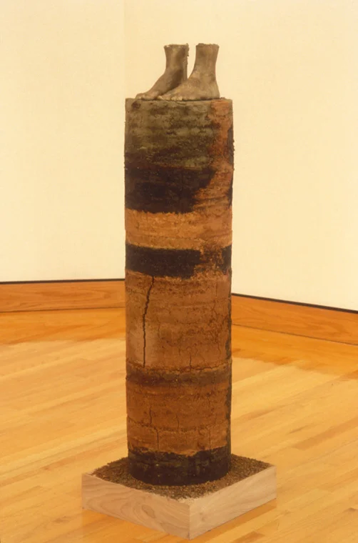 CORE SAMPLE: SELF PORTRAIT 1994 earth from every place I've lived, 1" equals 1 year, earth from Missouri, Louisiana, Illinois, Alabama, Minnesota, Maine, Missouri, Glue, life cast bronze of my feet , cylinder, 43" x 12".