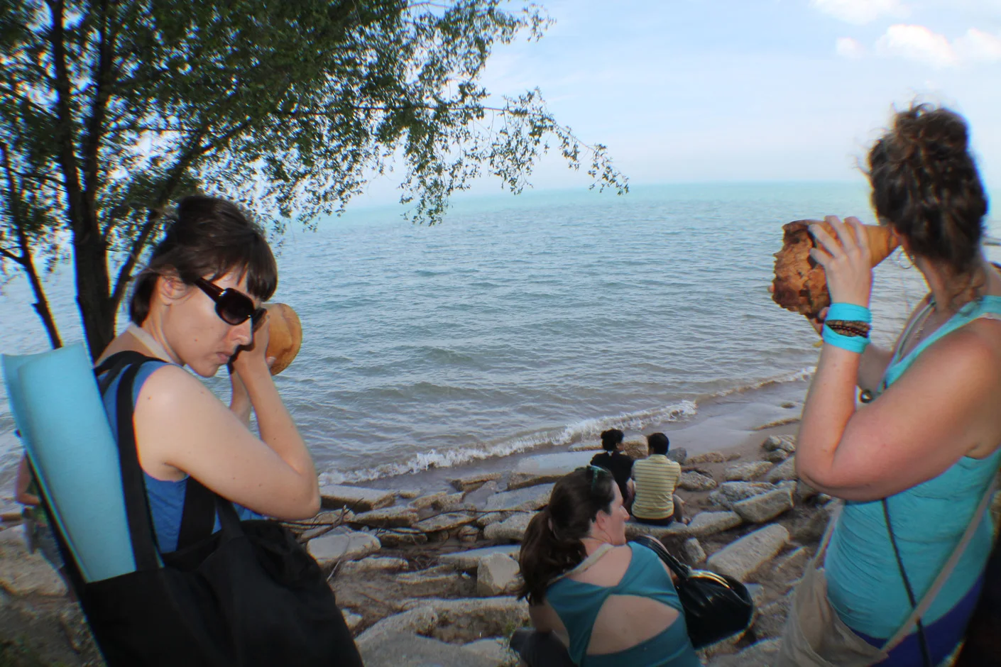 Listening to waves striking the rocks at Hartigan Beach, ten hand carved wooden burl trumpets used by participants, walk planned and led by Karen McCoy, sponsored by Alternative Spacetime 1300 (artist residency), Chicago, IL. (photo: Caro d’Offay)