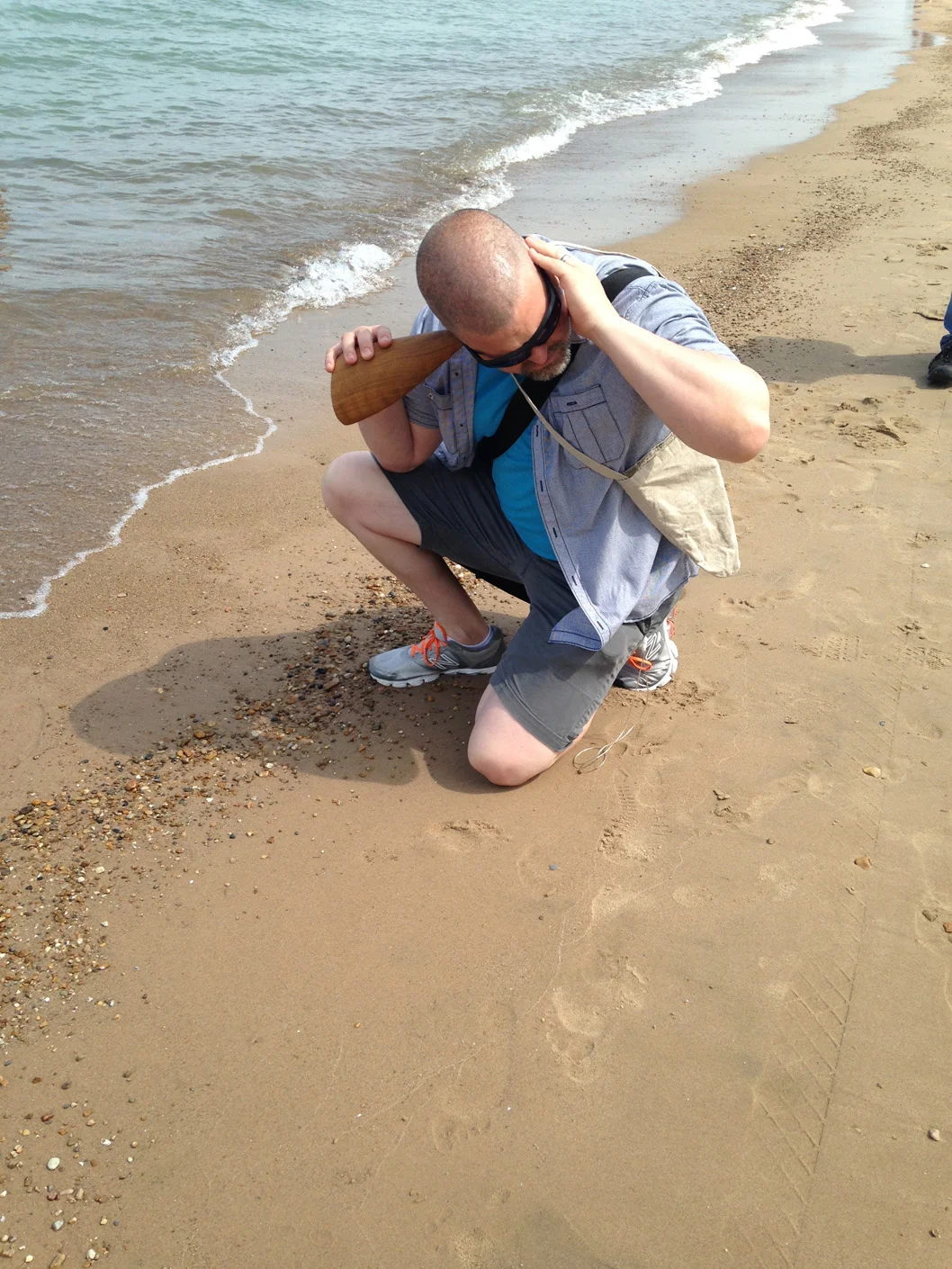 Listening to water lapping the Tony Prinz Beach, hand carved wooden burl trumpet in use, walk planned and led by Karen McCoy, sponsored by Alternative Spacetime 1300 (artist residency), Chicago, IL. (photo: Karen McCoy)