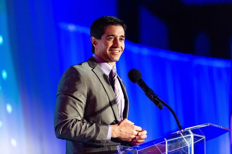 Carlo Capua smiling while speaking at a podium