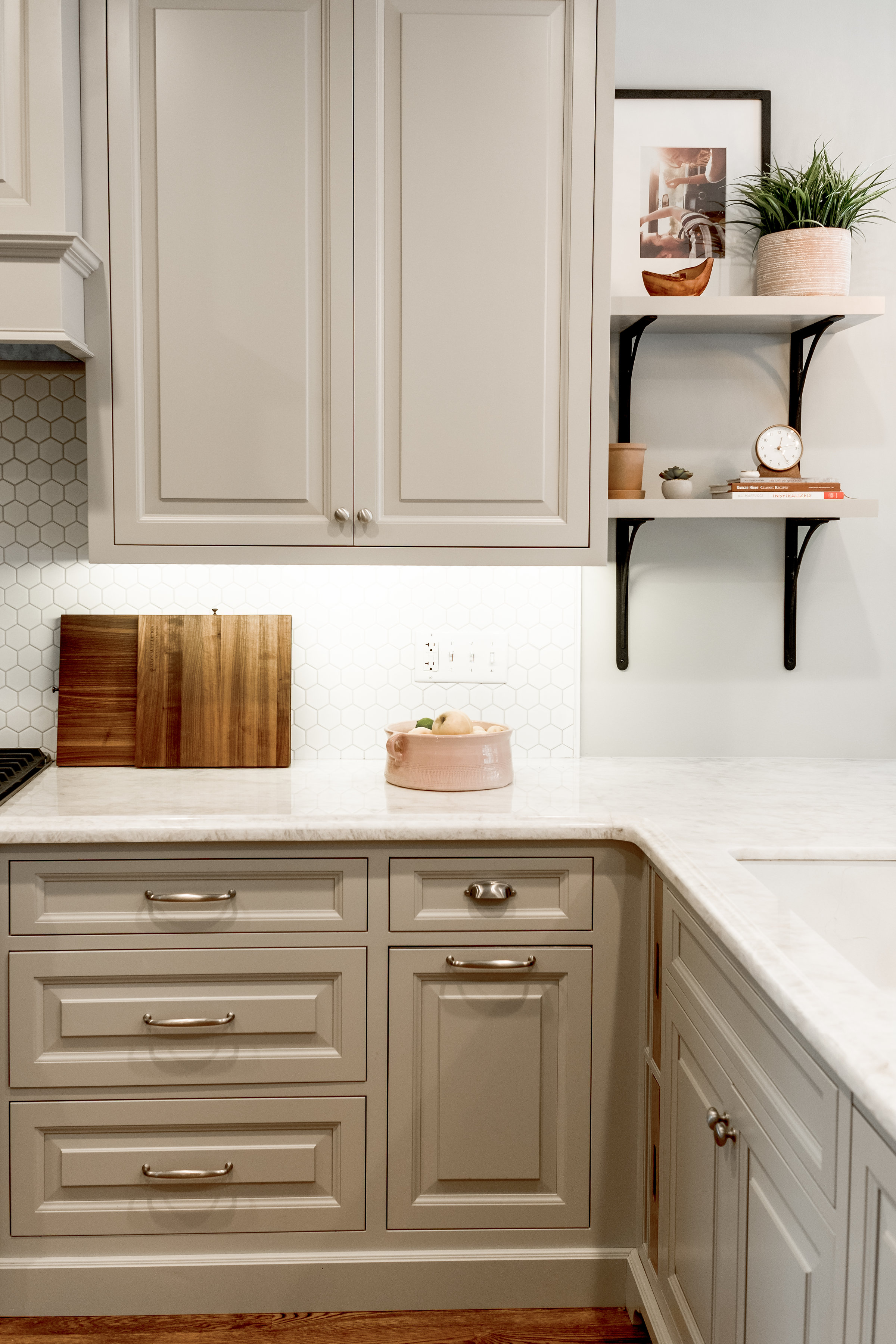 Taupe custom cabinets with styled open shelving and hexagon backsplash