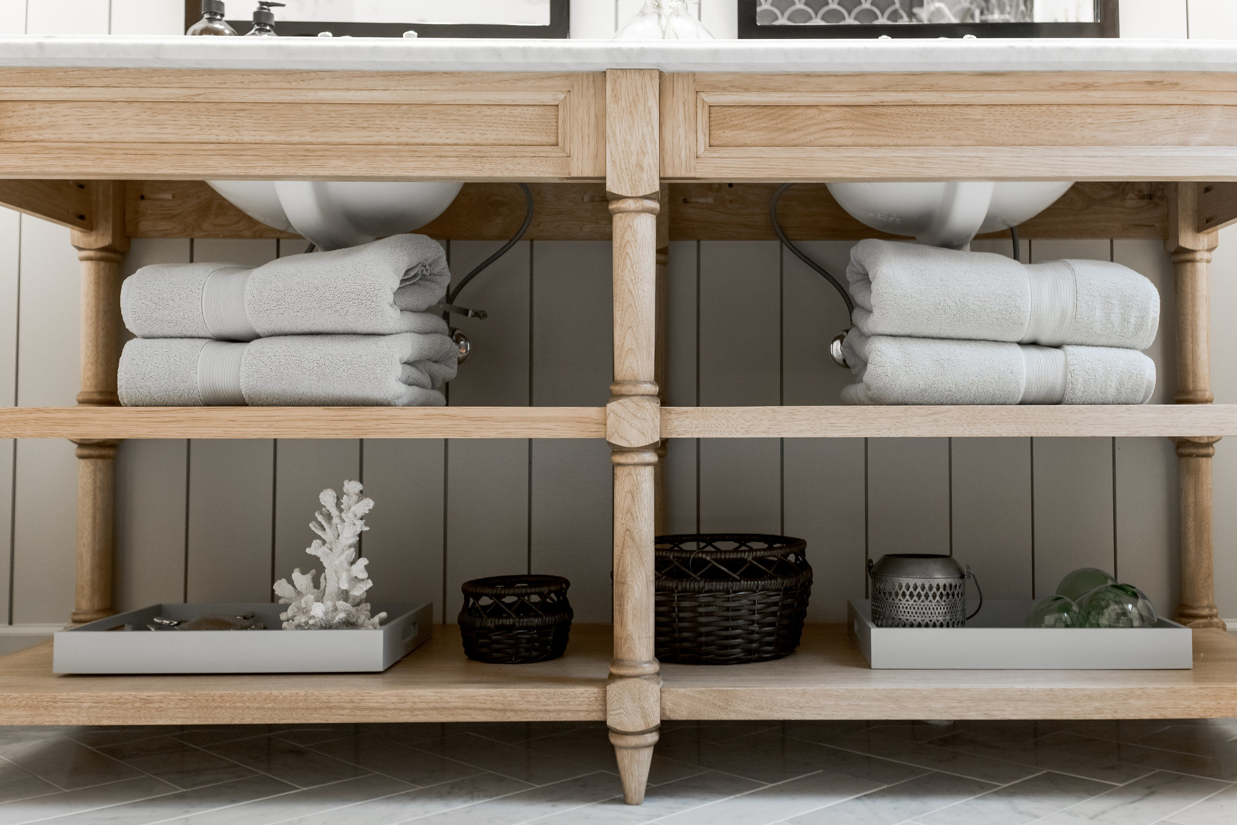 Wood vanity with open shelves, white stone countertops and vintage style mirrors