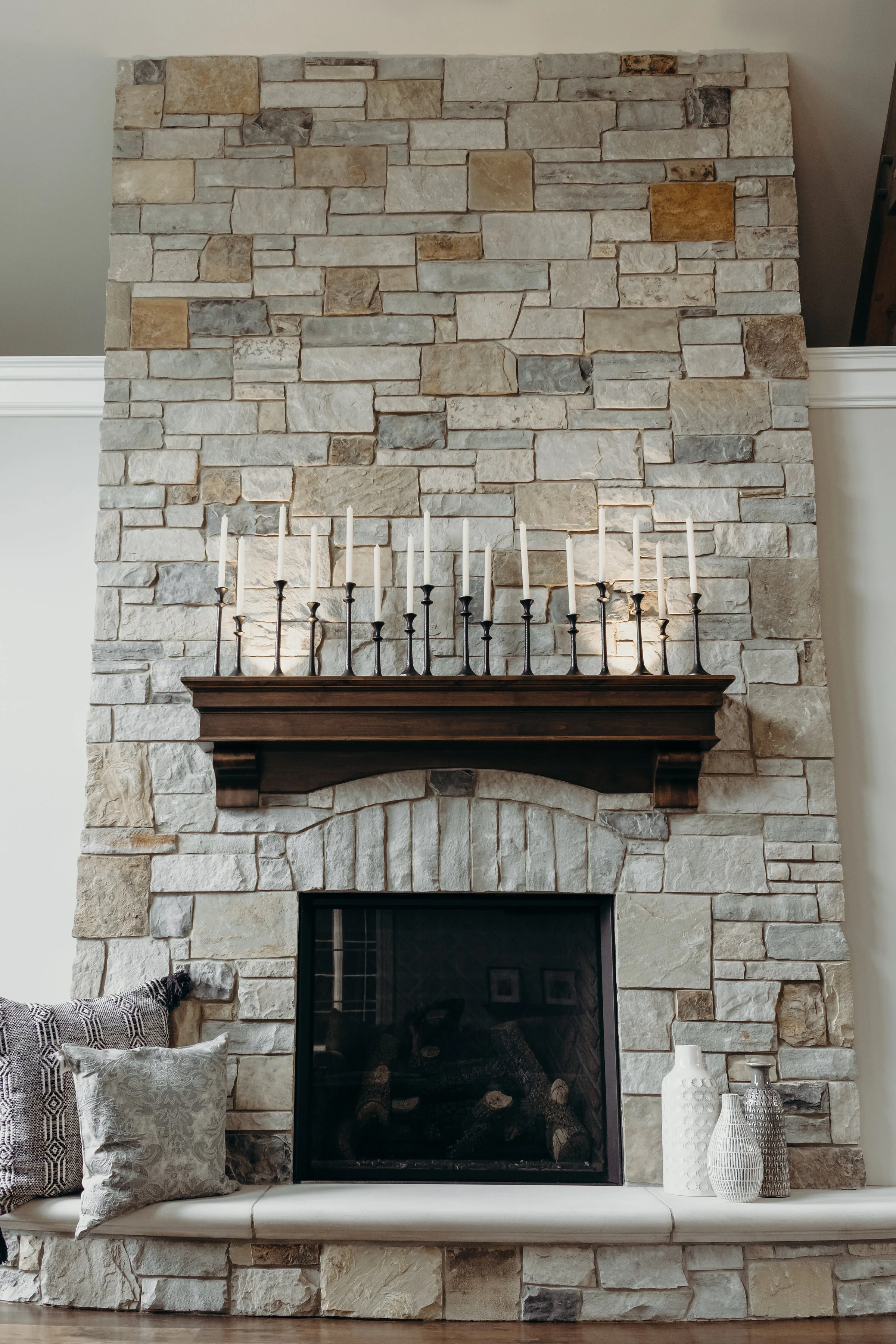 Fireplace decorated with candles, pillows and vases
