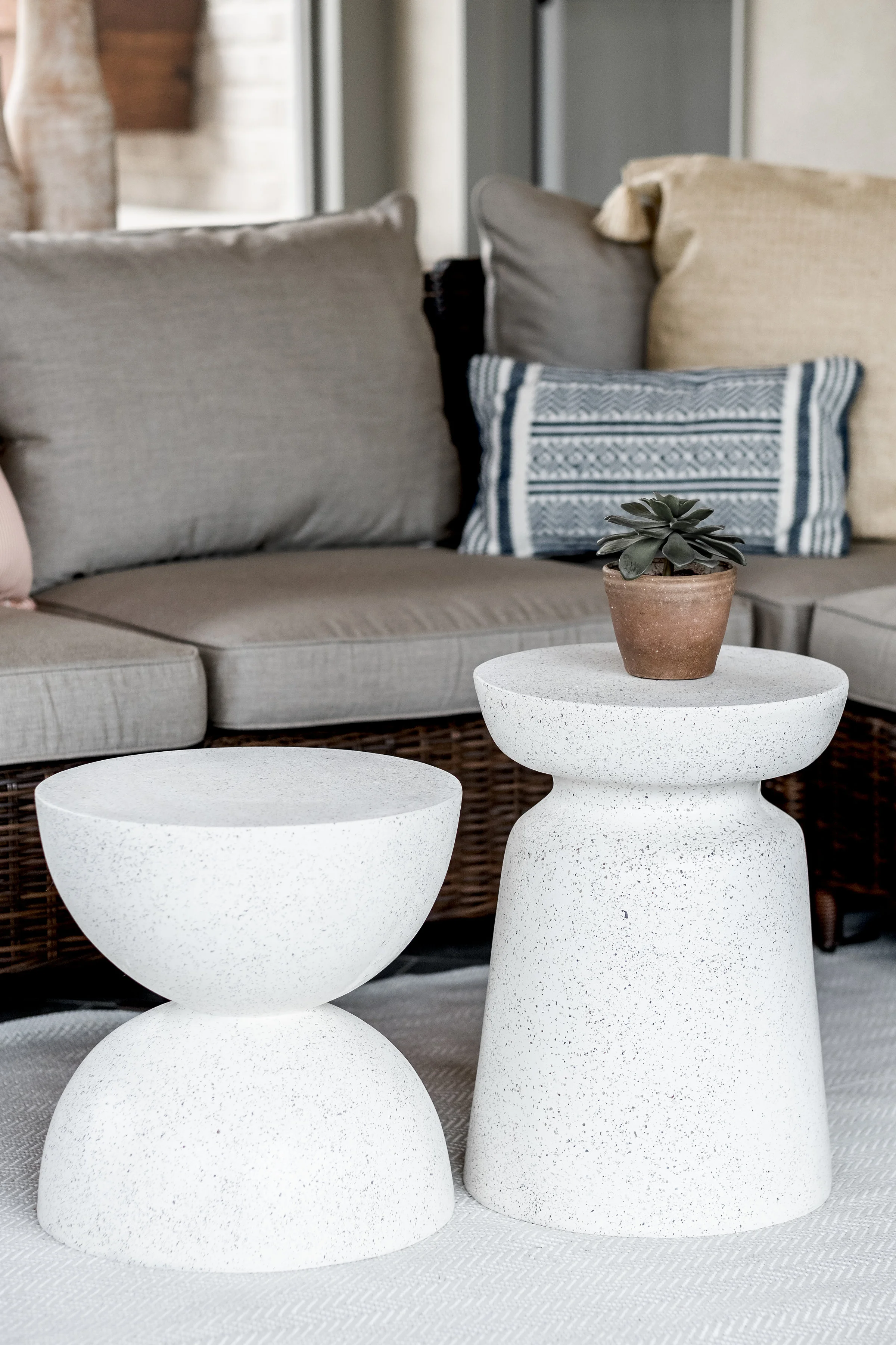 Stone white accent tables next to sectional in covered porch