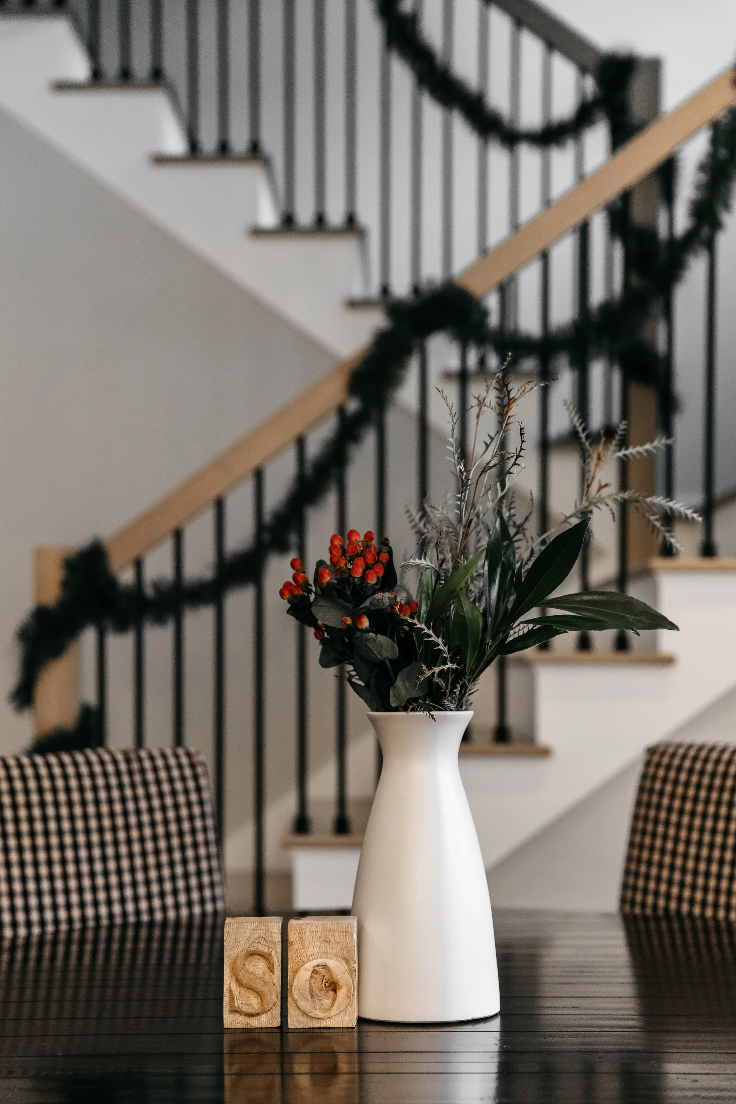 Dining table with floral centerpieces and garland wrapped staircase