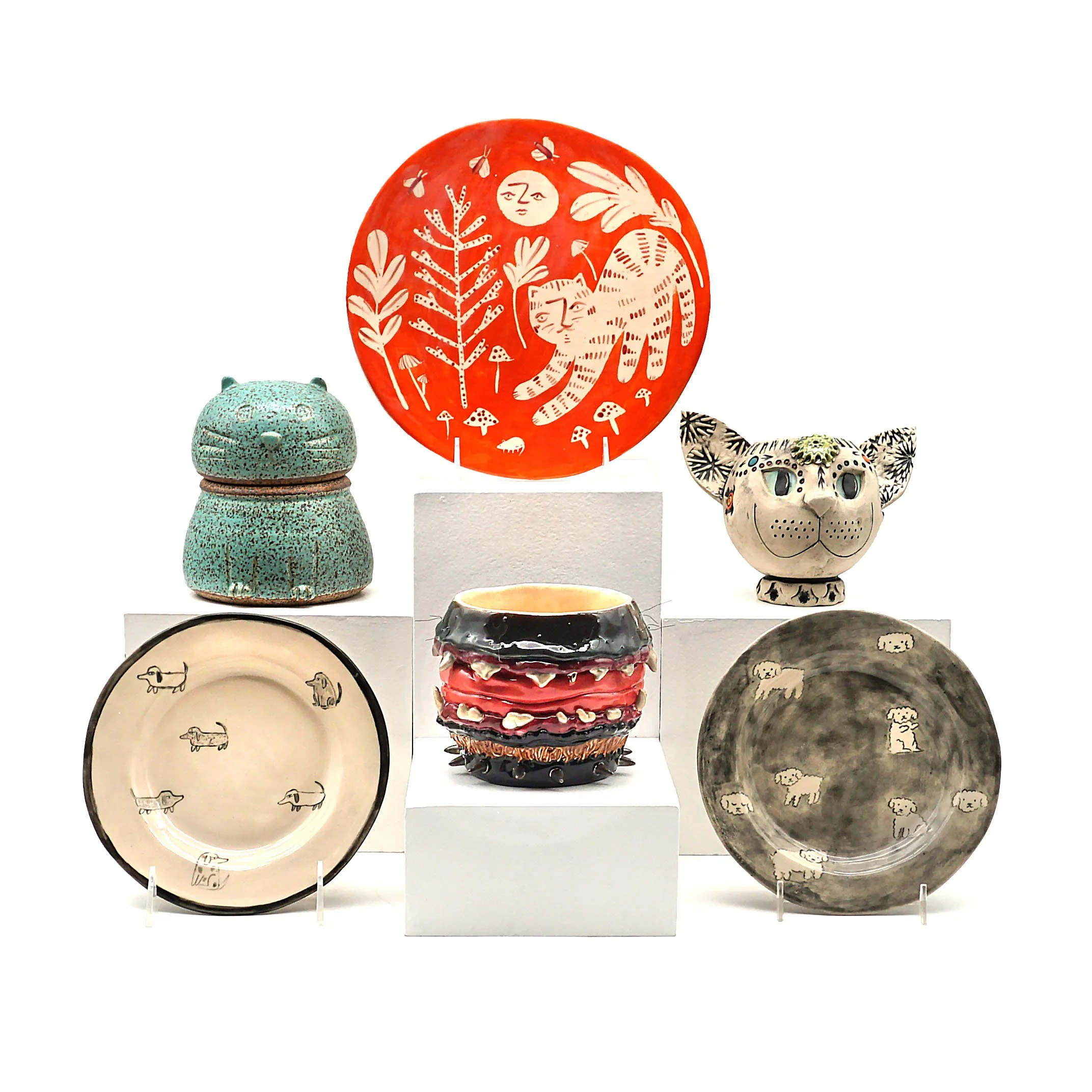 Bottom left (clockwise): "Dog Plate" by Steph Becker, "Cat Jar" by Paul Mallory, "Forest Cat Plate" by Kate Skelly, "Cat Head Vessel - Ozma" by Desiree Warren, "Slobber Trough" by Logan Reynolds. 