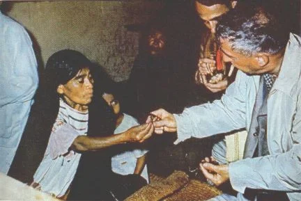 RECEIVING his mushrooms, Wasson takes his night's ration from the hand of Curandera Eva Mendez. In right background Guy Stresser-Péan, French anthropologist who accompanied Wasson, has begun to chew his own supply.