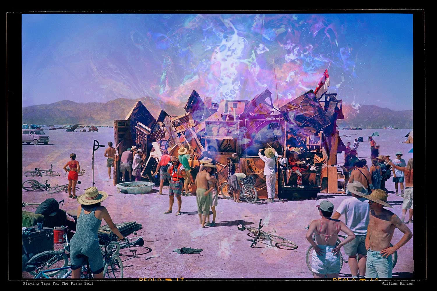 William Binzen ’s “Playing Taps for the Piano Bell”. William’s Notes on the Photo : In 1996 Steve Heck delivered 100 spent pianos to the playa. He handed out boxes of sticks. The inevitable result was achieved – a gluttonous cacophony of odd and curious sonorities. Playa carpenter ants went to work banging and clanging on strings that protruded everywhere from the two-story high aggregation of sound boards. Talk about a soundscape of joyful noise! Players of all skill levels were called into action. It was a volksmusik of playa muscle. I made two images of the Piano Bell: this one, and another done at night. "Playing Taps" is about the community spirit that coalesces around a focal point like the Bell, and jumps in and gets involved. The ebb and flow of sound has its visual echo in the fire-y wraiths and vapors rising from the piano. I asked myself: How do you convey sound and feelings (not just depictions) of celebration in a still photograph? And I began playing with the idea of synesthesia. If you stare at a visual representation of sound, can you better imagine the experience of being wrapped in a cacophony of noise with sonorous overtones? Can you better re-create the experience of being warm and happy and grooving in an atmosphere distant from where you are now as you read these words? If you bring your active imagination to thinking about this image, what then? Go to the kitchen and bang on pots and pans and glasses and dishes? Many drummers started out this way. The man dressed in white and wearing a straw hat is the focalizer. Visually, he sets the tone and tempo. He’s the turbulator. The lead musician for a group that doesn’t need a lead. It’s really a self-directed free-for-all. It’s a celebration, and it can be whatever thoughts you let fly over the abstract ‘smoke’ that rises from the bell. A smoke of personal alchemy in an image that could be a kind of yantra, an orchestrated image that, despite its cacophonous energy, can transport the viewer into a meditative state.