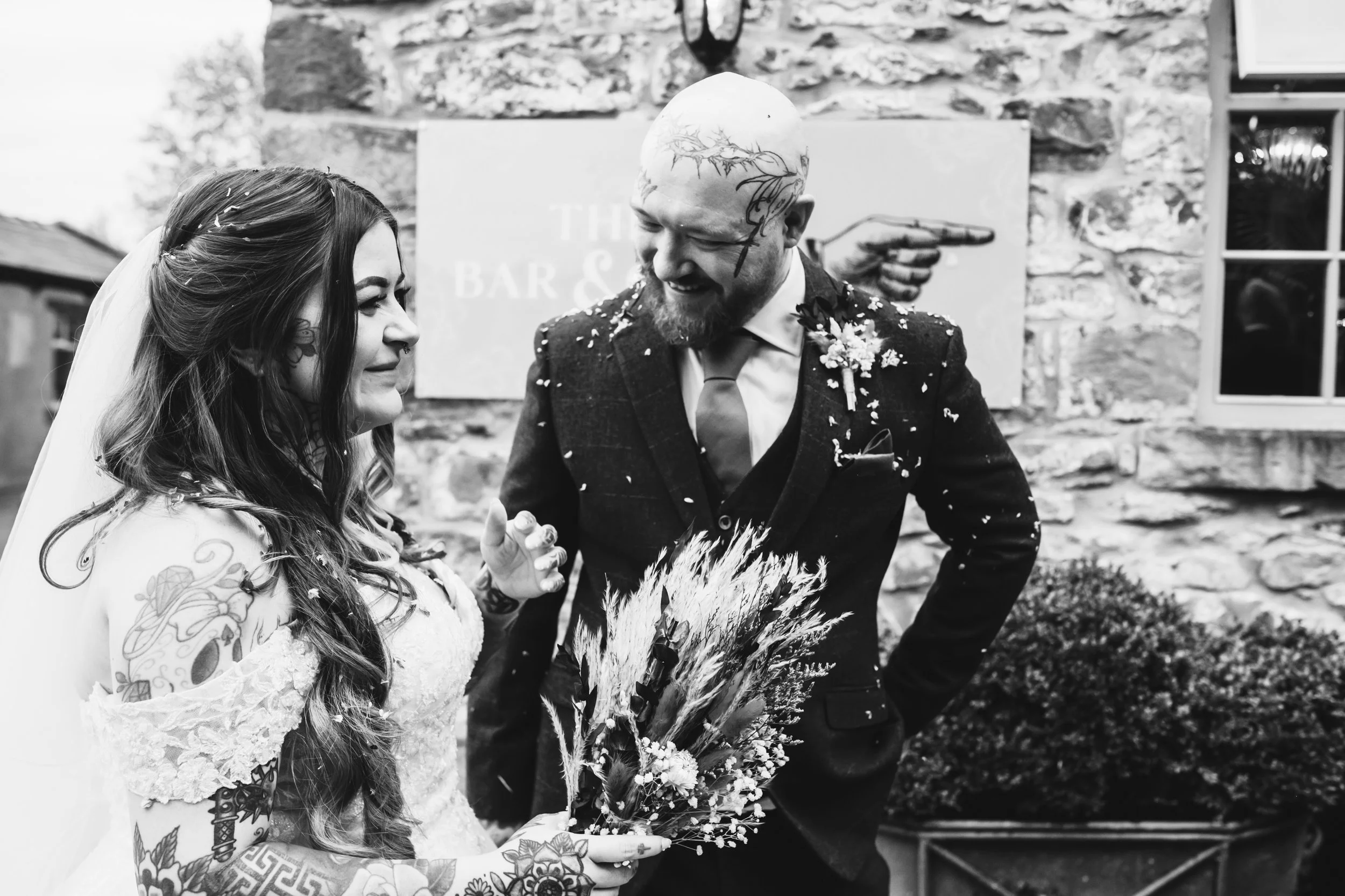 bride and groom covered in confetti, laughing, wedding dress, wedding flowers. editorial wedding photography