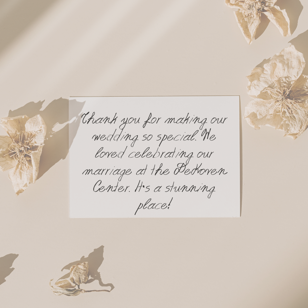 A handwritten wedding thank you note on white paper surrounded by dried flowers, with sunlight casting soft shadows.