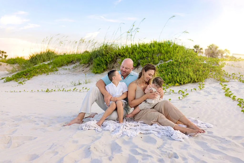 Ponte Vedra Beach photo session with family in blue shirt, beige dress, and neutral colors for kids in the sand dunes at sunset with golden hour light over plants