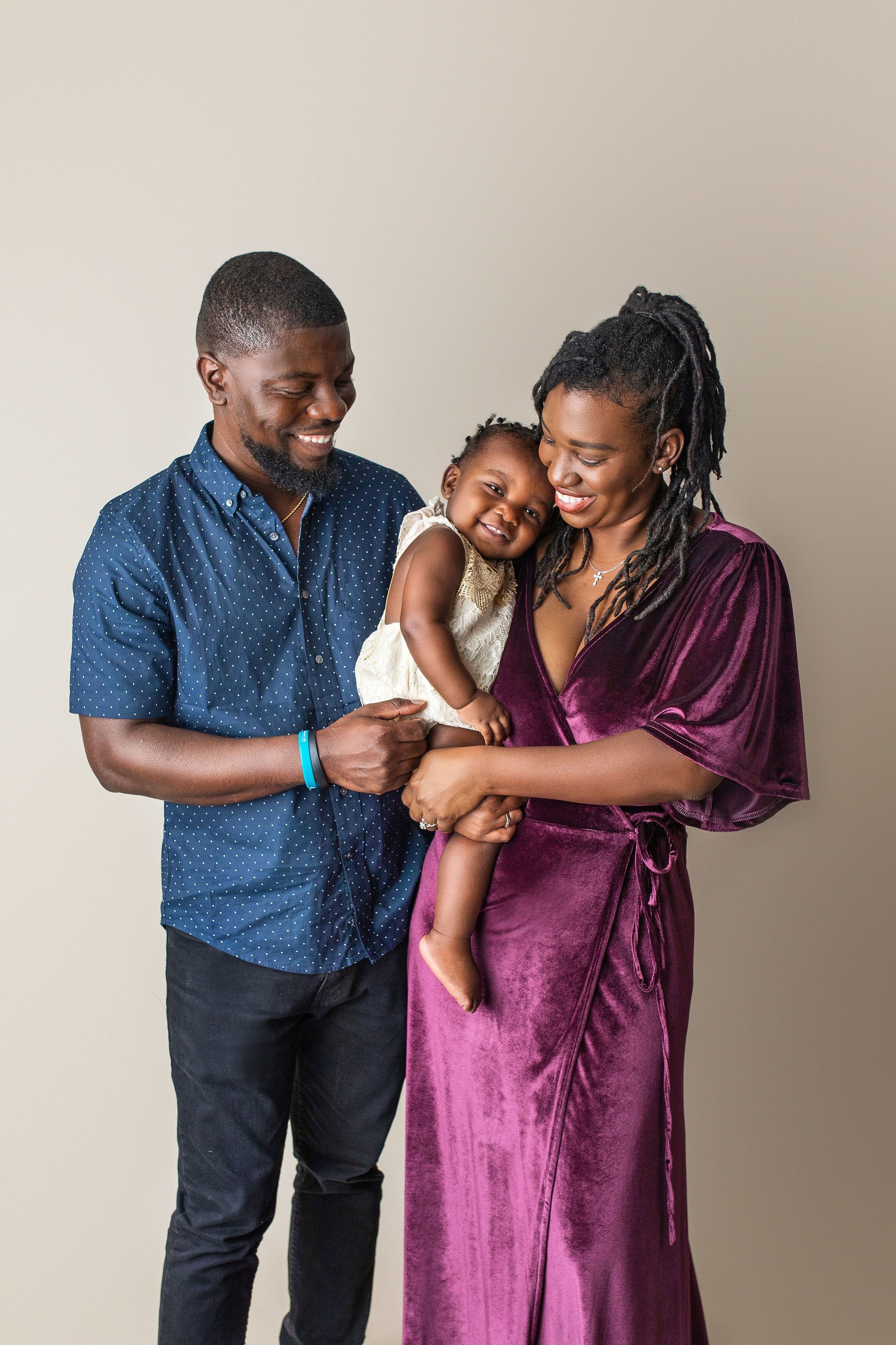 Family photos with african american couple and baby girl in Palm Coast FL photography studio using neutral tones and luxury gowns