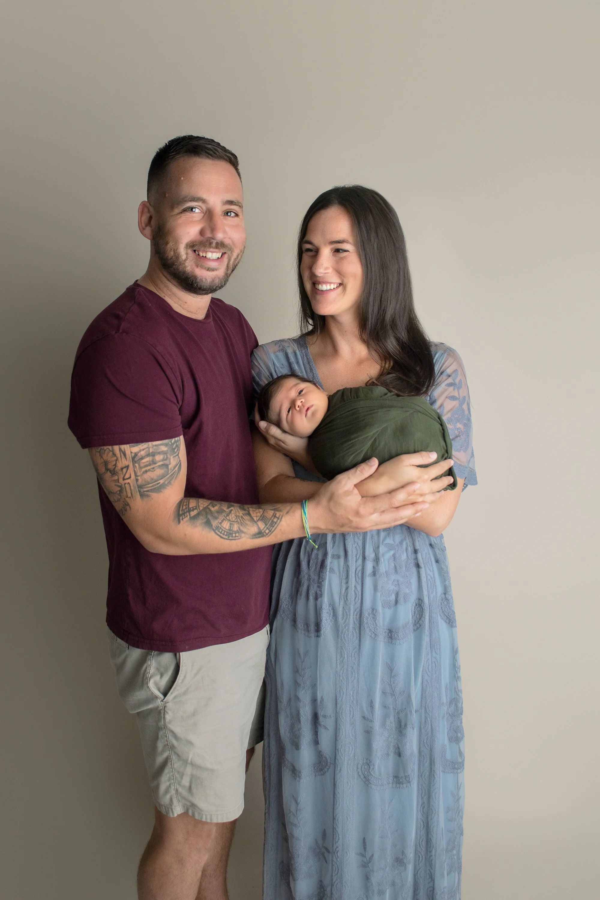 Parent photos with baby boy from Ponte Vedra FL with mom in blue gown, baby in green wrap, dad in red earth tone