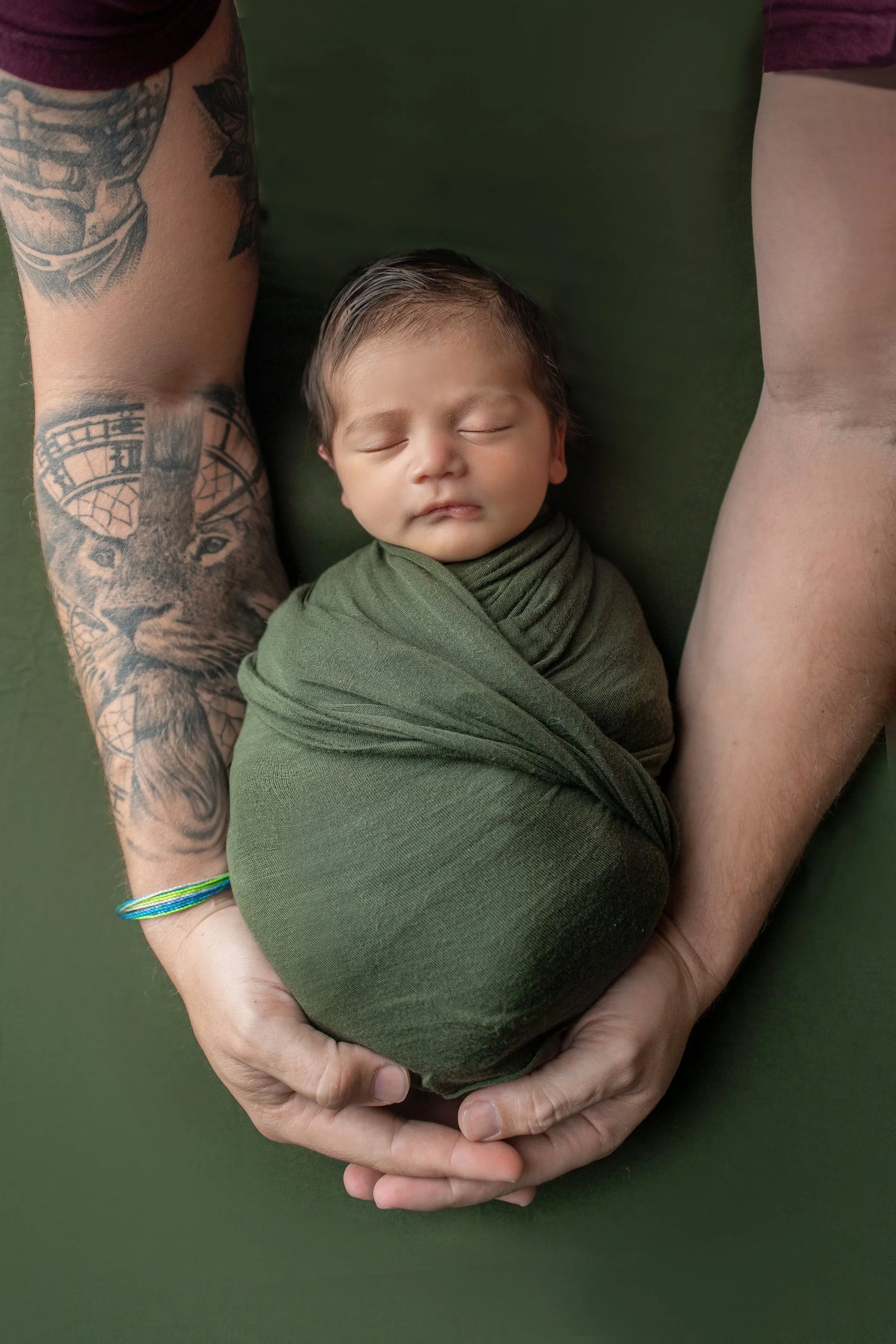 Ponte Vedra private photo studio with baby boy on olive green with wrap and dad's hands with tattoos