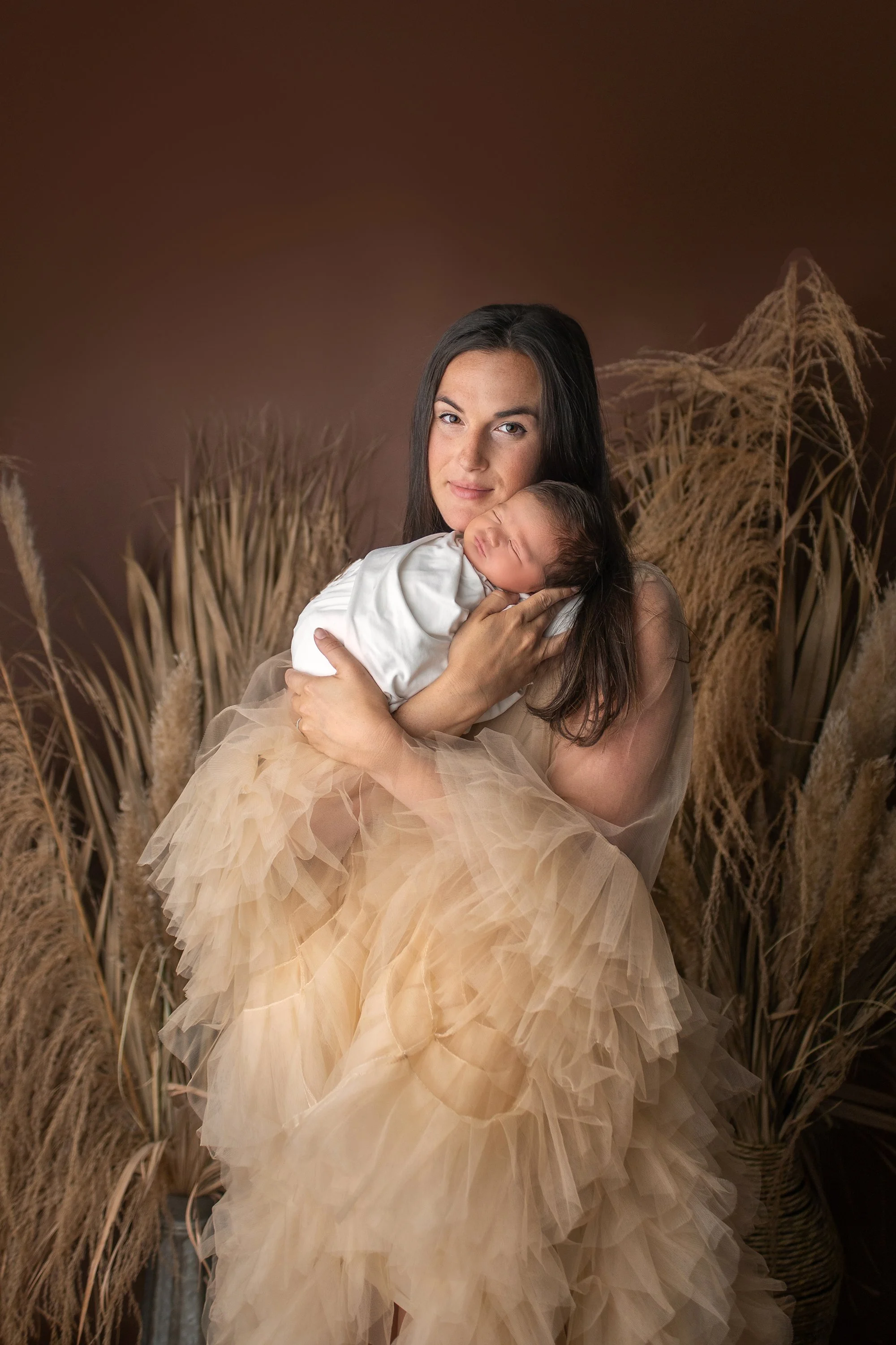 Ponte Vedra newborn photo session with baby boy in white wrap, mom in beige tulle dress gown, and boho grasses and brown background