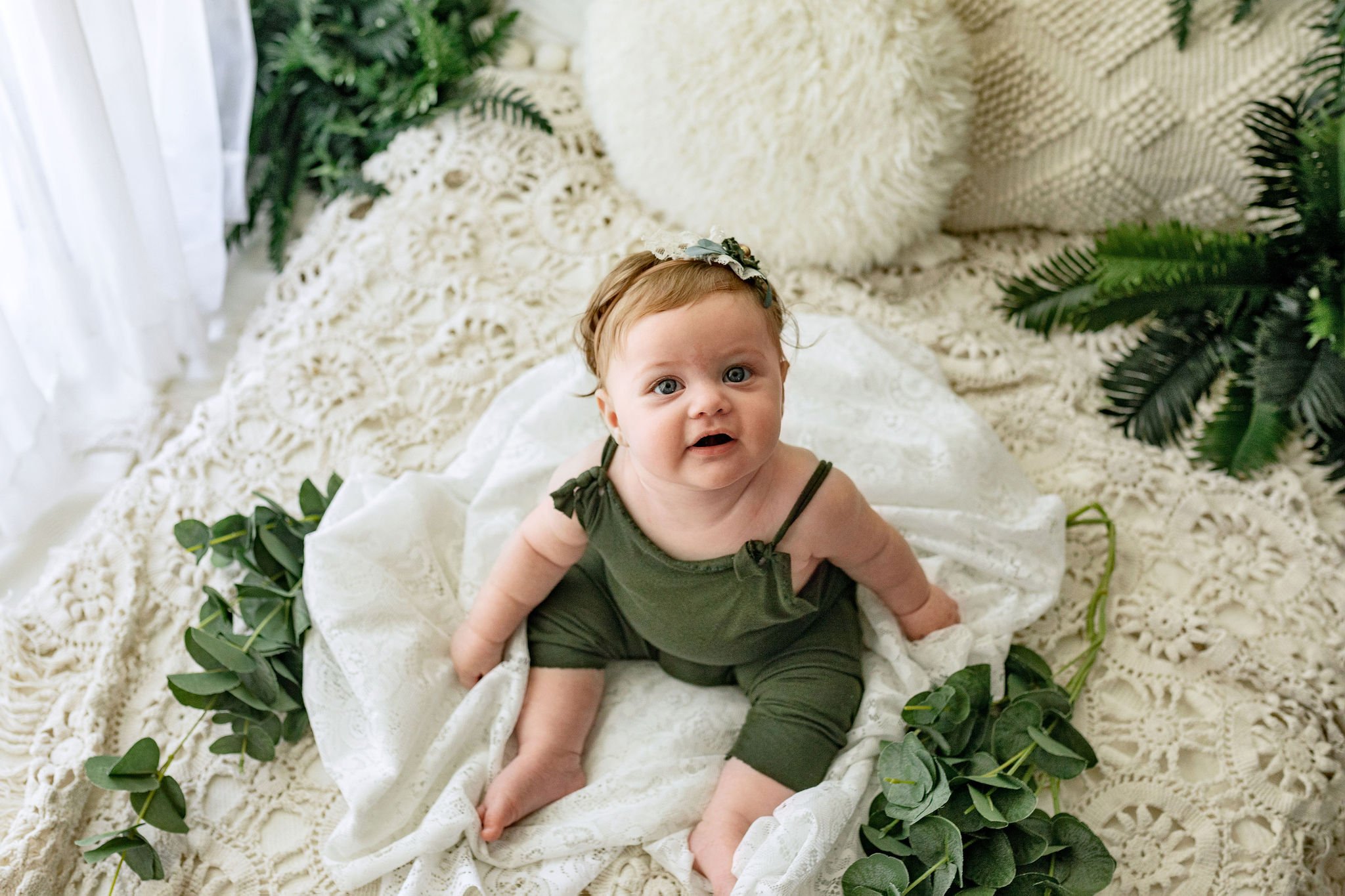 Boho milestone session with 6 month old baby girl wearing earth tone overalls and organic style bow in hair sitting in family photo studio doing pictures with child photographer in Ponte Vedra, FL