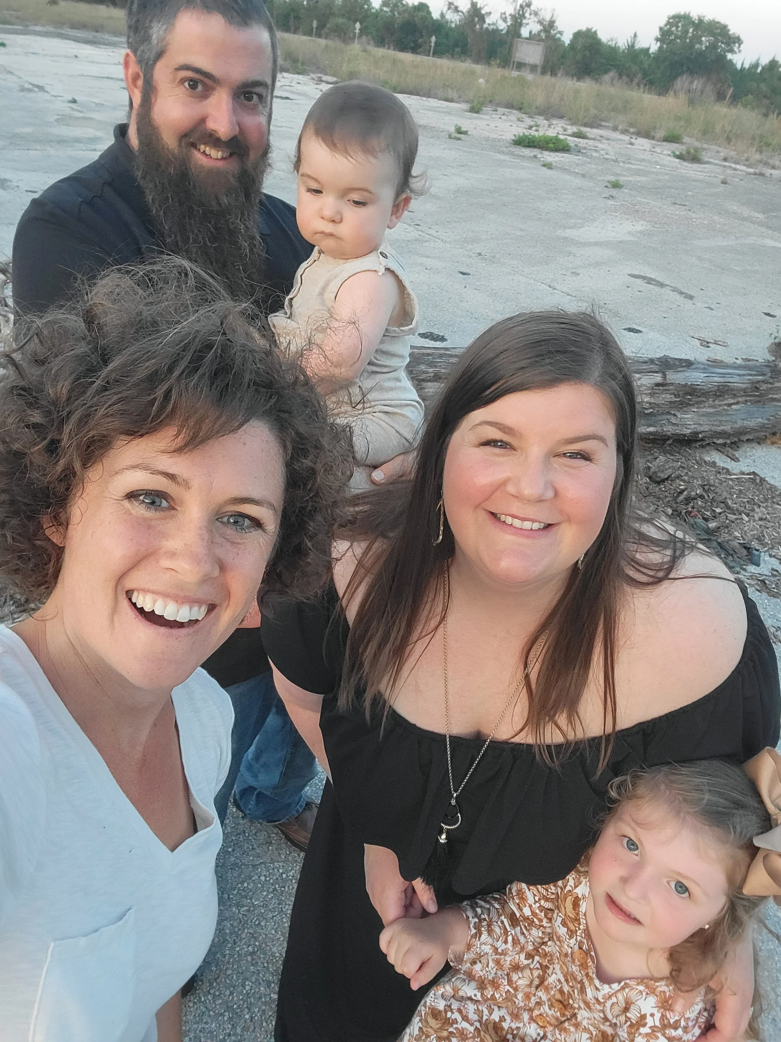Group of adults and two children posing outdoors in Palm Coast, FL in boho grasses and outdoor location at sunset.