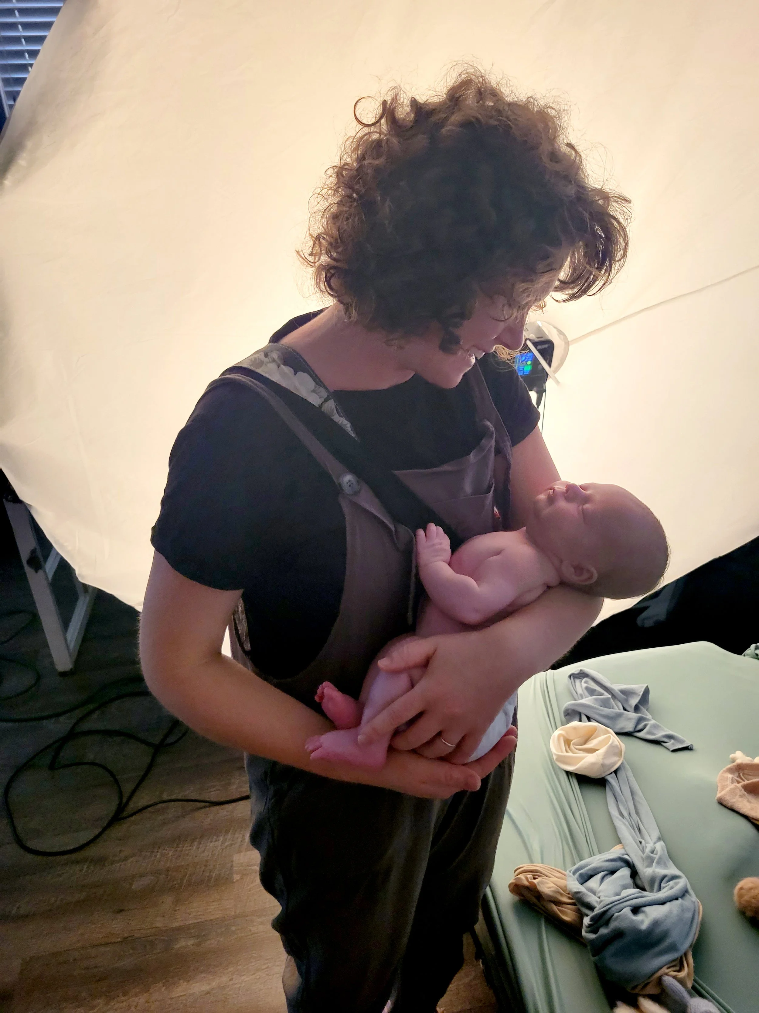 JAX, FL best newborn photogapher holding a baby under soft indoor lighting.