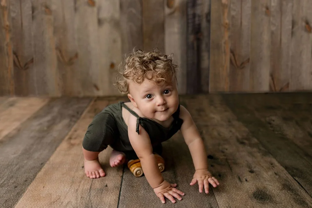 Milestone photo shoot in STA, FL with 9 month old baby boy in earth tone overalls and wooden background with olive green overalls