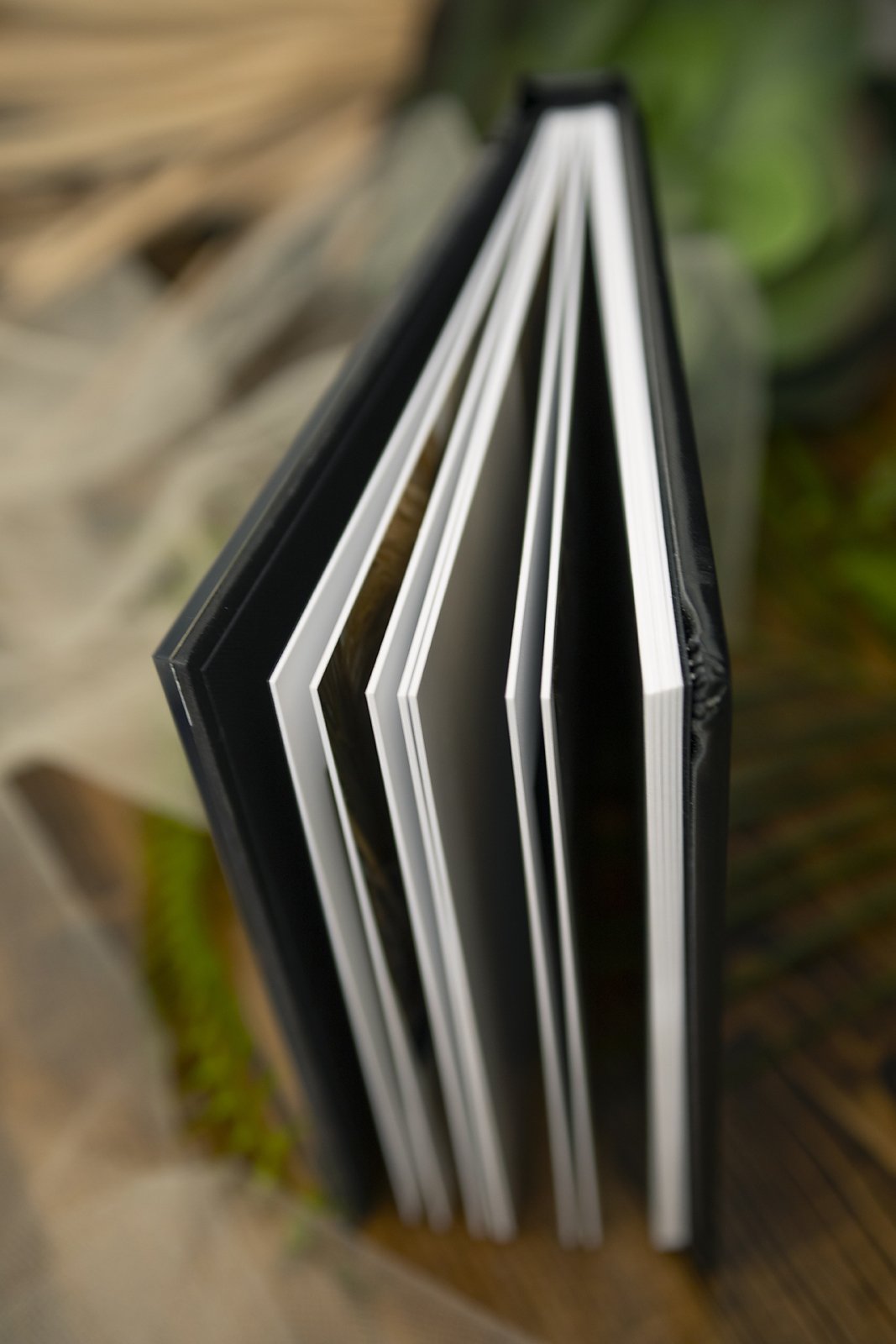 Open photo album with thick pages on a textured background in photography studio in Ponte Vedra, FL with best newborn photographer.