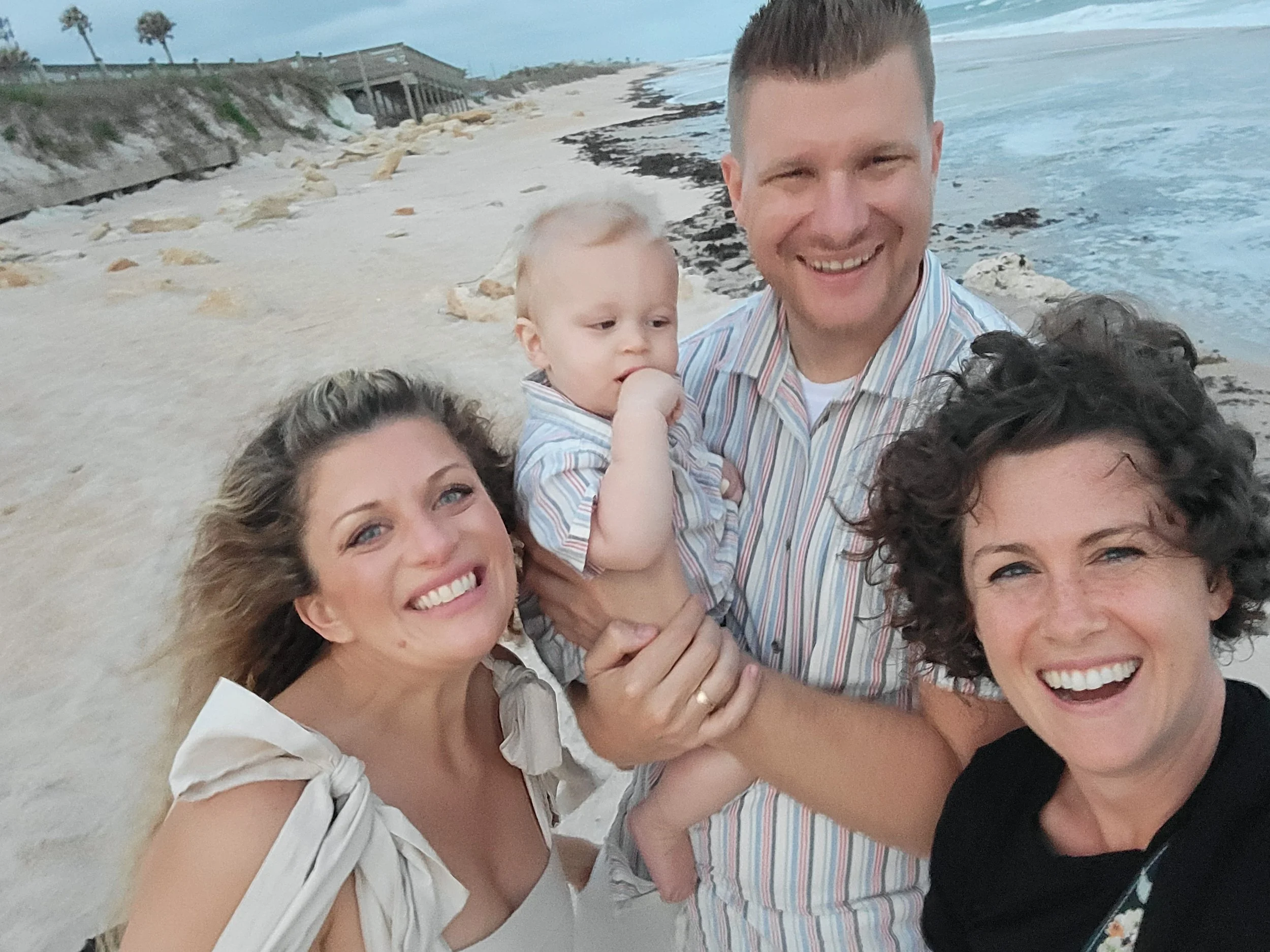 Jacksonville FL luxury family photographer at sandy beach with the ocean in the background with baby and couple on vacation.